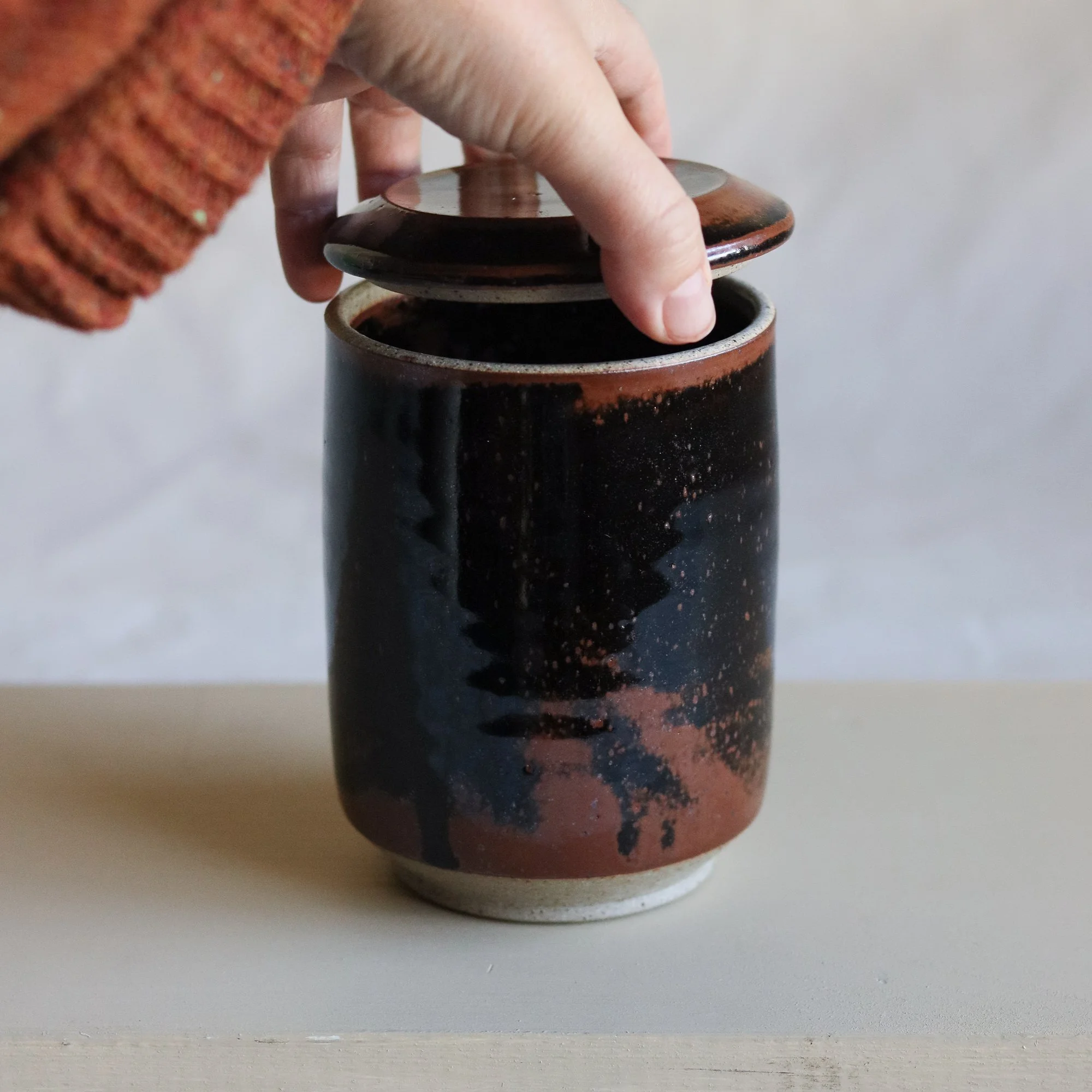 Hand putting a lid on to the sourdough jar in tenmoku