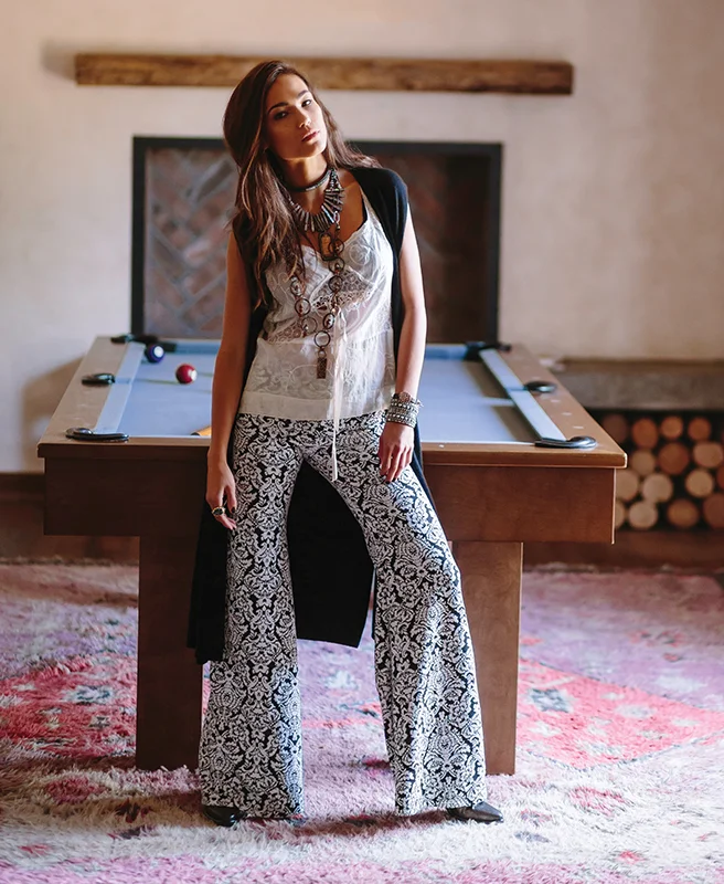 Christopher Fischer sweater vest, Chasen. Nightcap printed flare pant, Rowan. Crowheart chain necklace, Buddha necklace, bracelet, Antoinette. Huit lace bra, Bella Notte cami, Intimo. Charlie Hunt beaded choker, Outpost Trading Co. Blue Topaz ring, ARA Collection. Gianluca Tombolini boots, Calleen Cordero studded cuff, Romp.