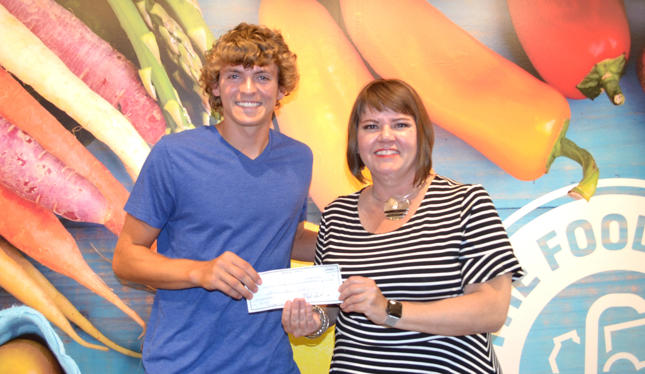 Alec Adair presents a check for $402 for Buddy Packs in Cooper County to The Food Bank Executive Director Lindsay Young Lopez.