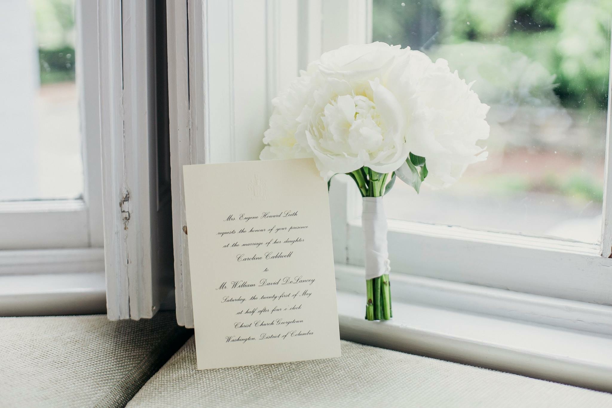 White bridal bouquet and wedding invitation