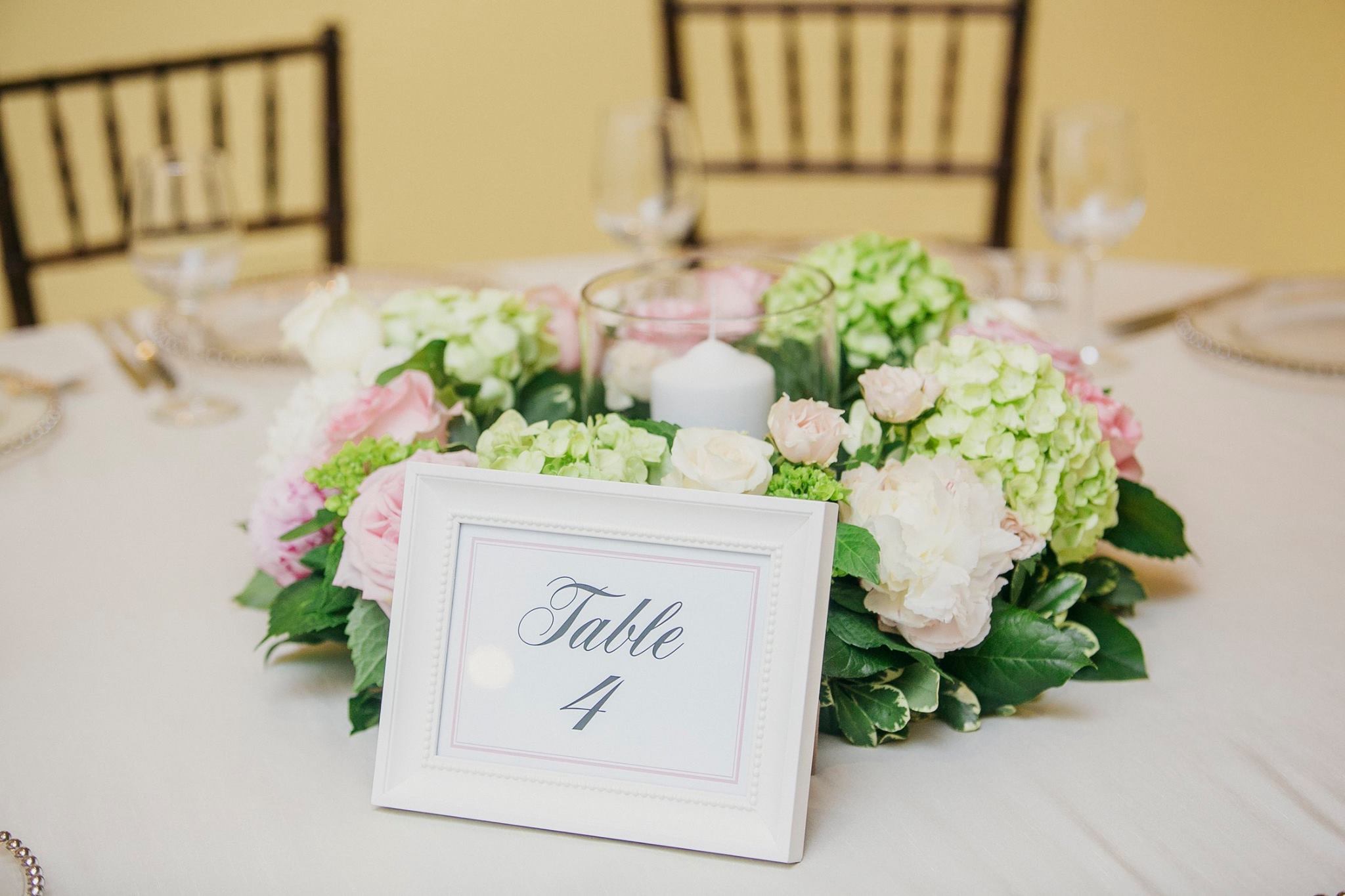 Wedding reception table with large pink, white, and green floral centerpiece 