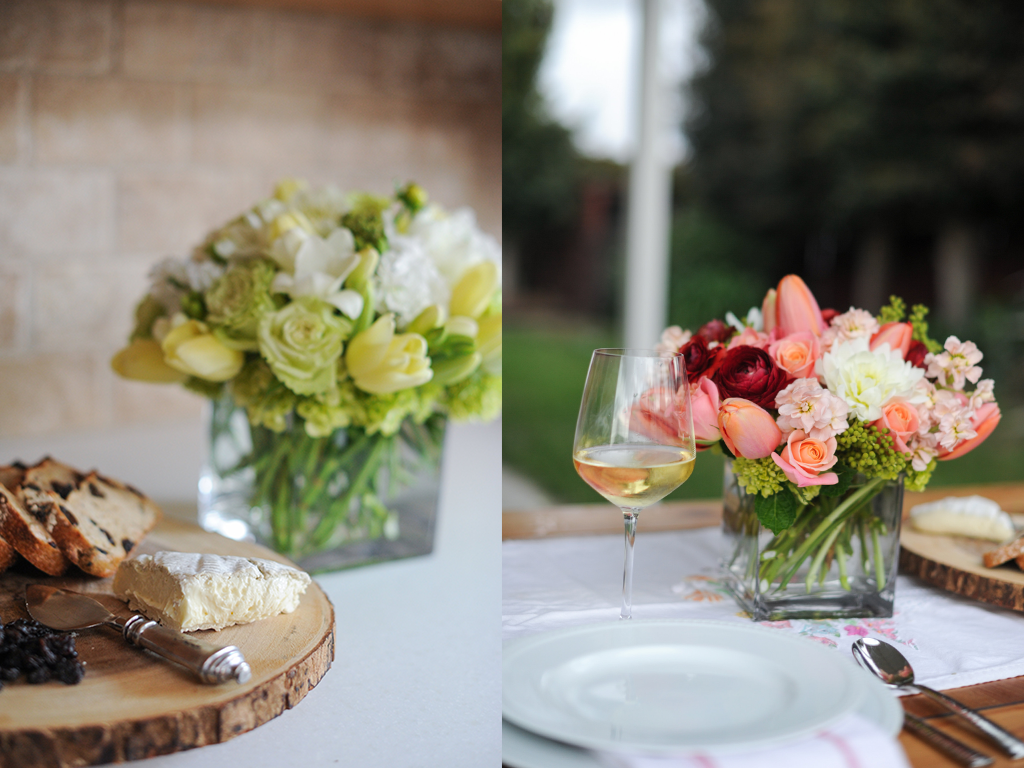 Cheese platter set in front of a white and yellow floral arrangement. Pink, red, and white flowers in a vase at a table setting.