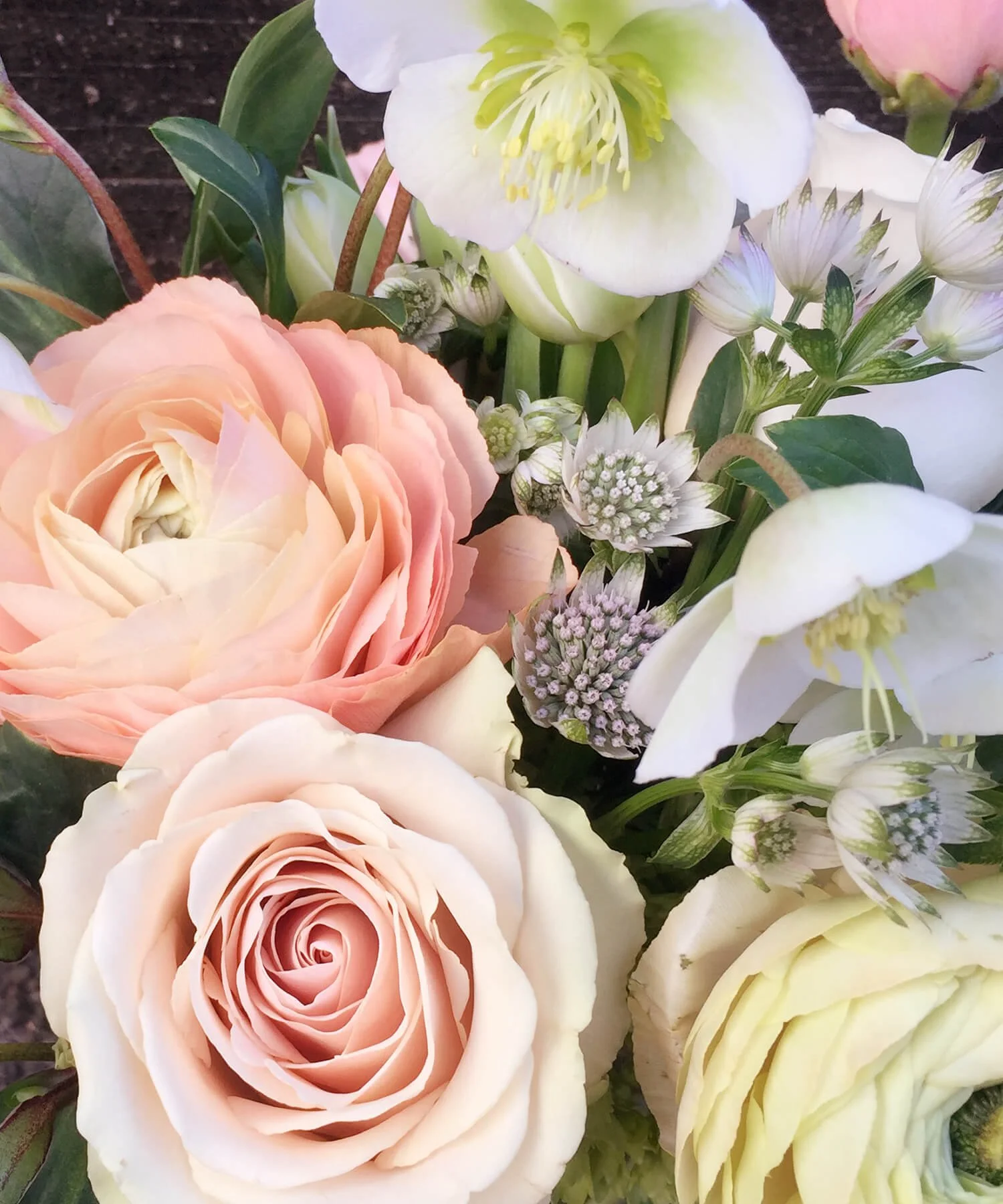 Peach and neutral pastel-hued roses, tulips, hellebore, ranunculus, sweet peas, lilac, and hydrangea