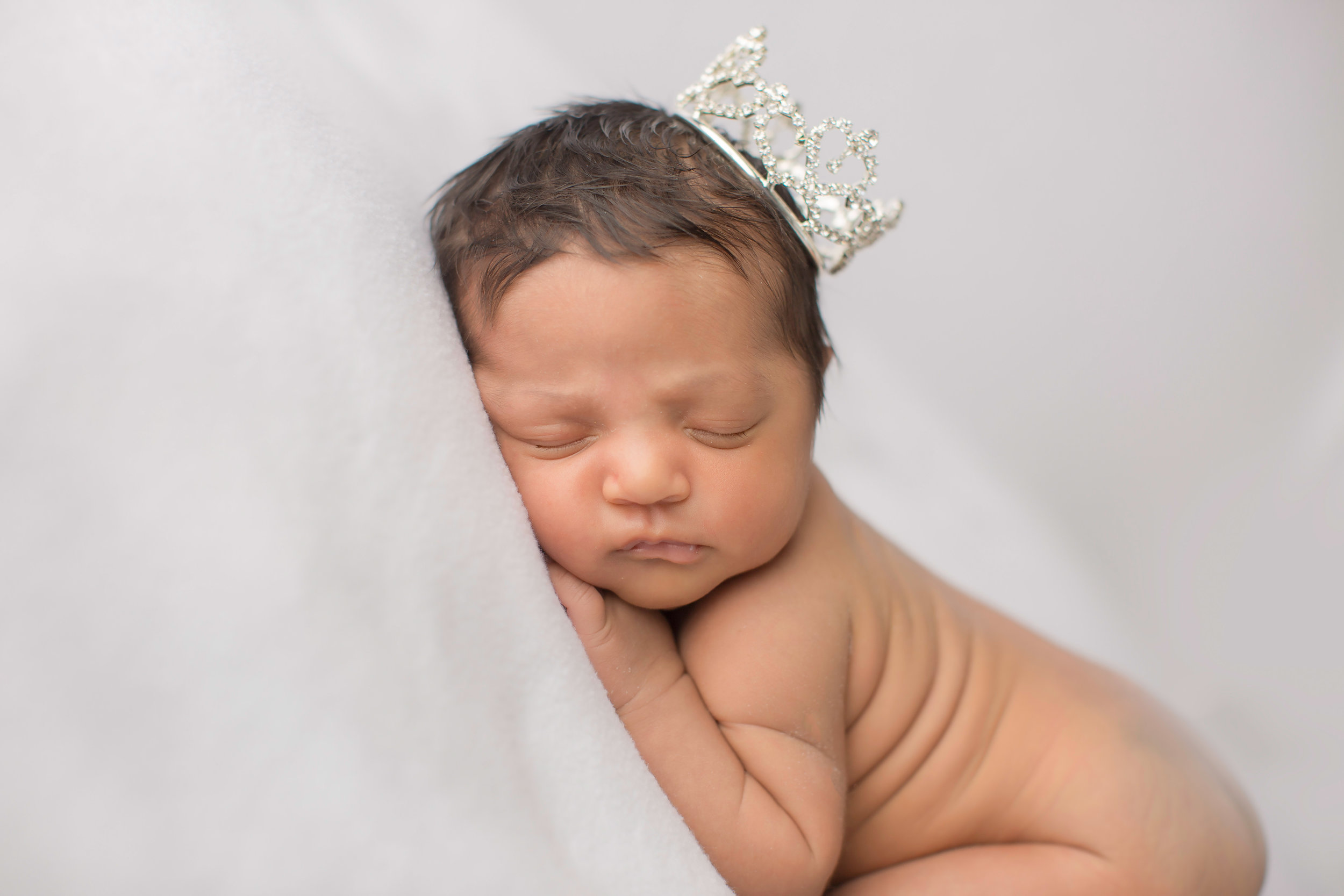  baby girl newborn with a crown on a neutral backdrop for newborn portraits 