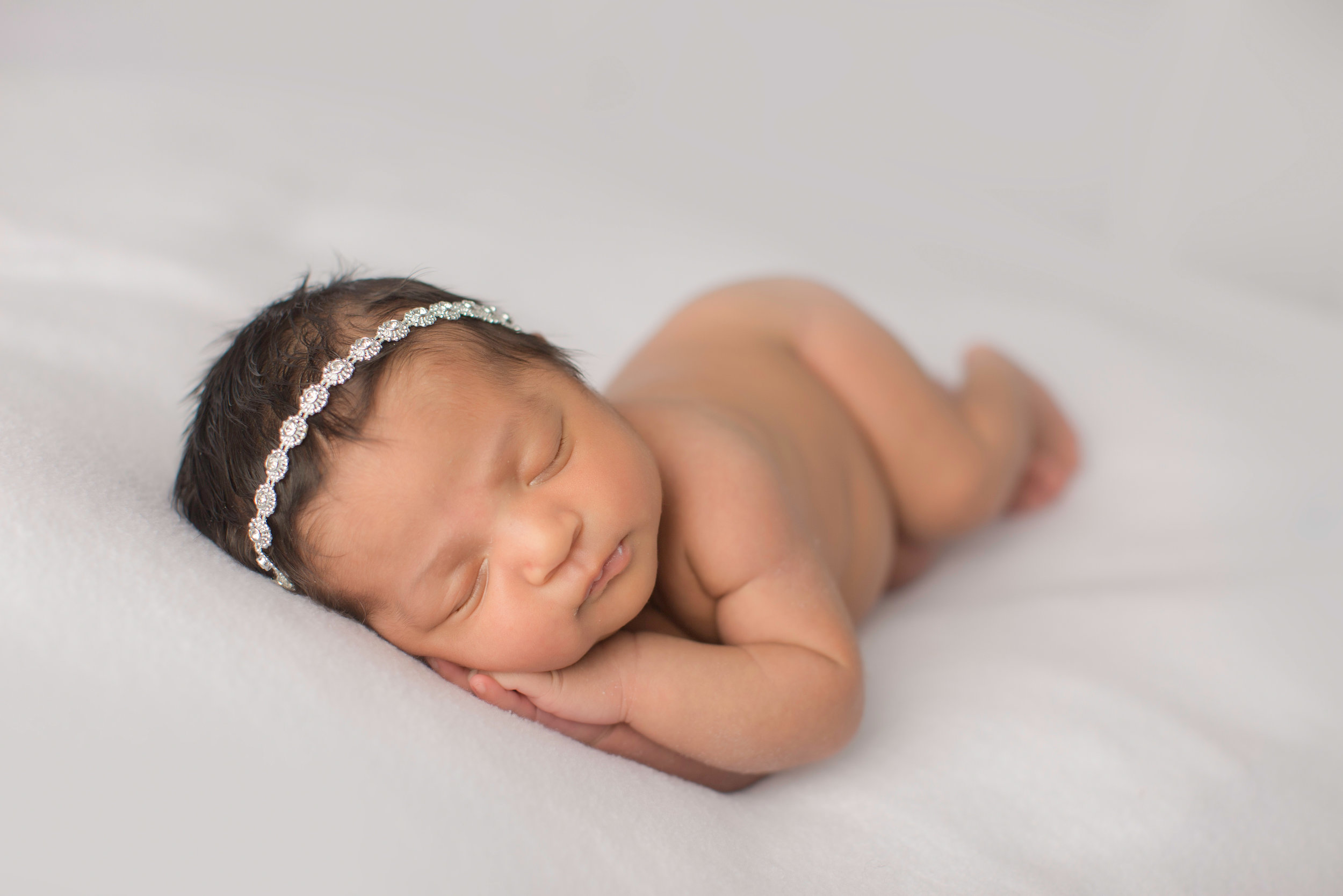  newborn baby girl in grand blanc michigan laying on her side with rhinestone headband 