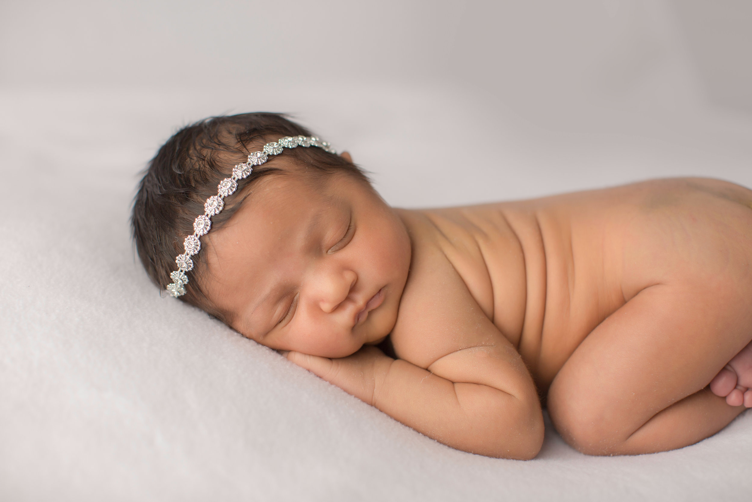  baby girl newborn laying on a neutral backdrop for portraits 