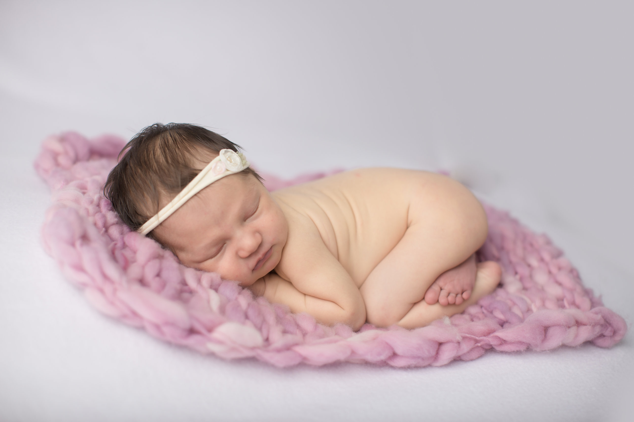  baby girl laying on a pick blanket during her Davison Michigan professional studio photography 