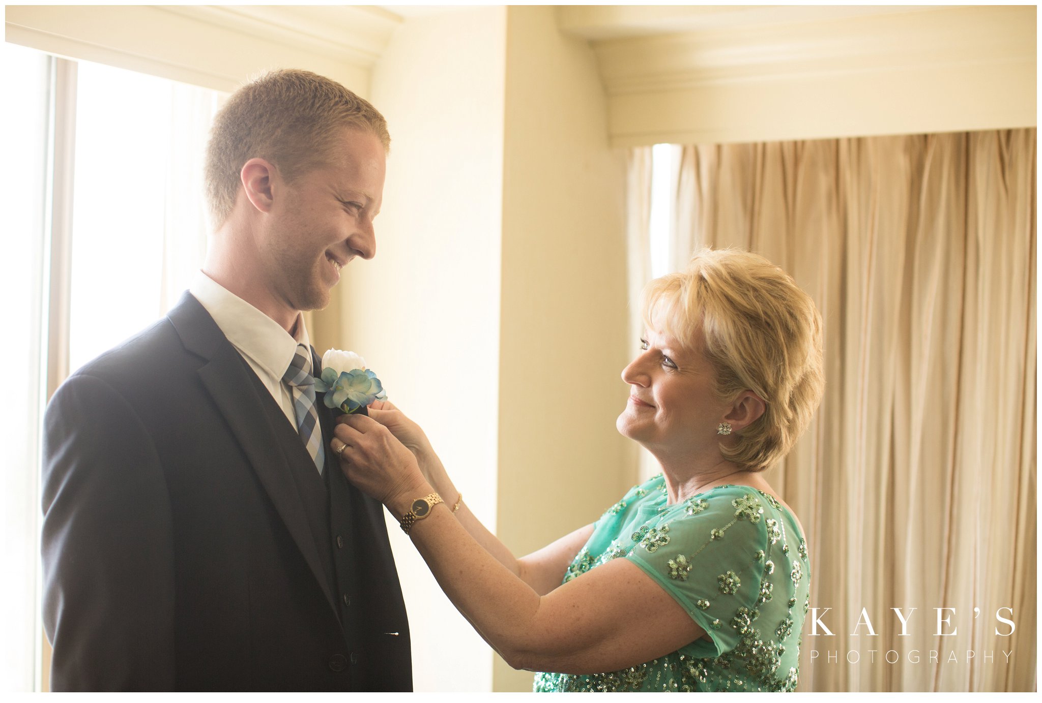 Groom's mother pinning groom while getting ready in plymouth, michigan