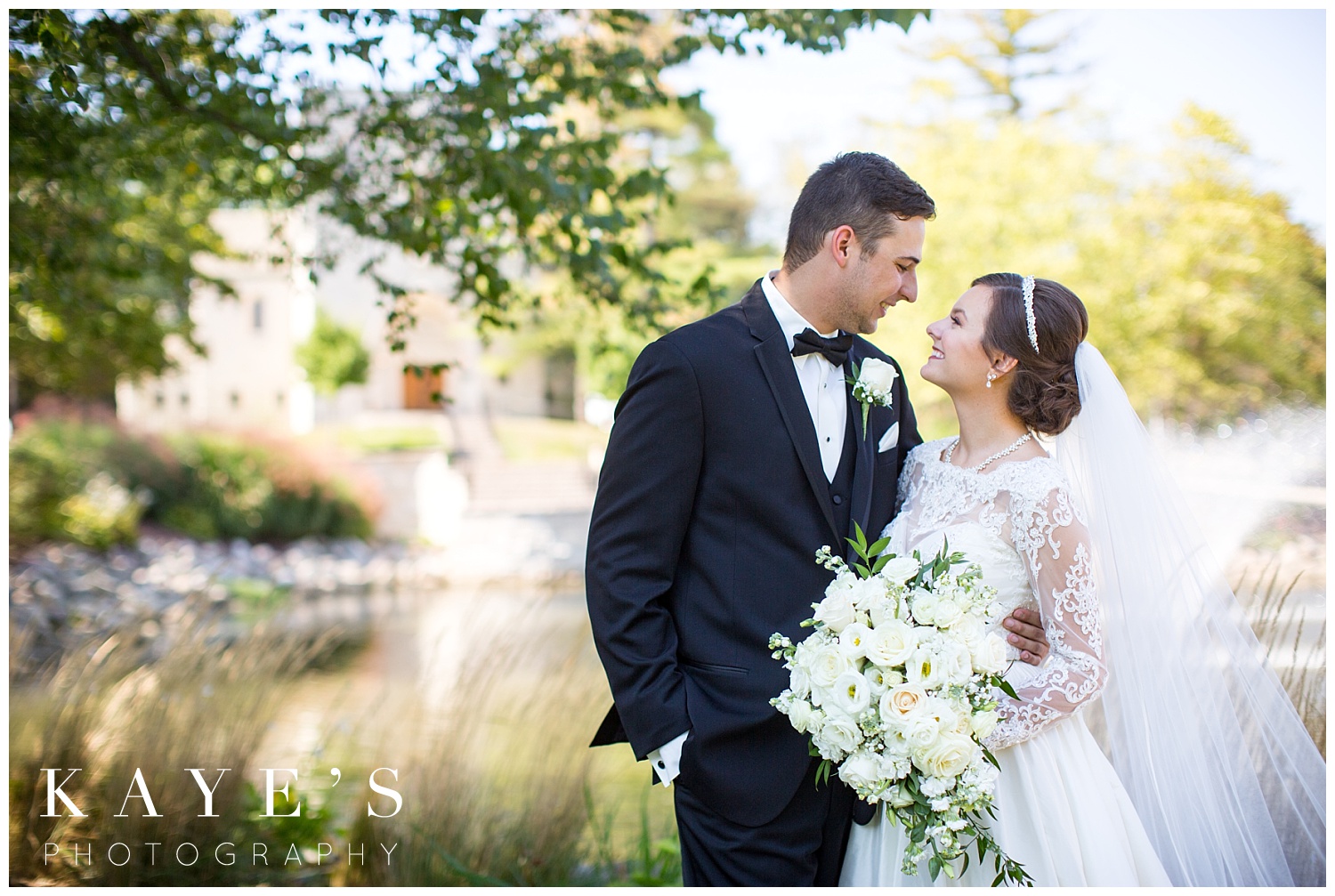 bride and groom posing in front of st. hugo catholic chruch on wedding day