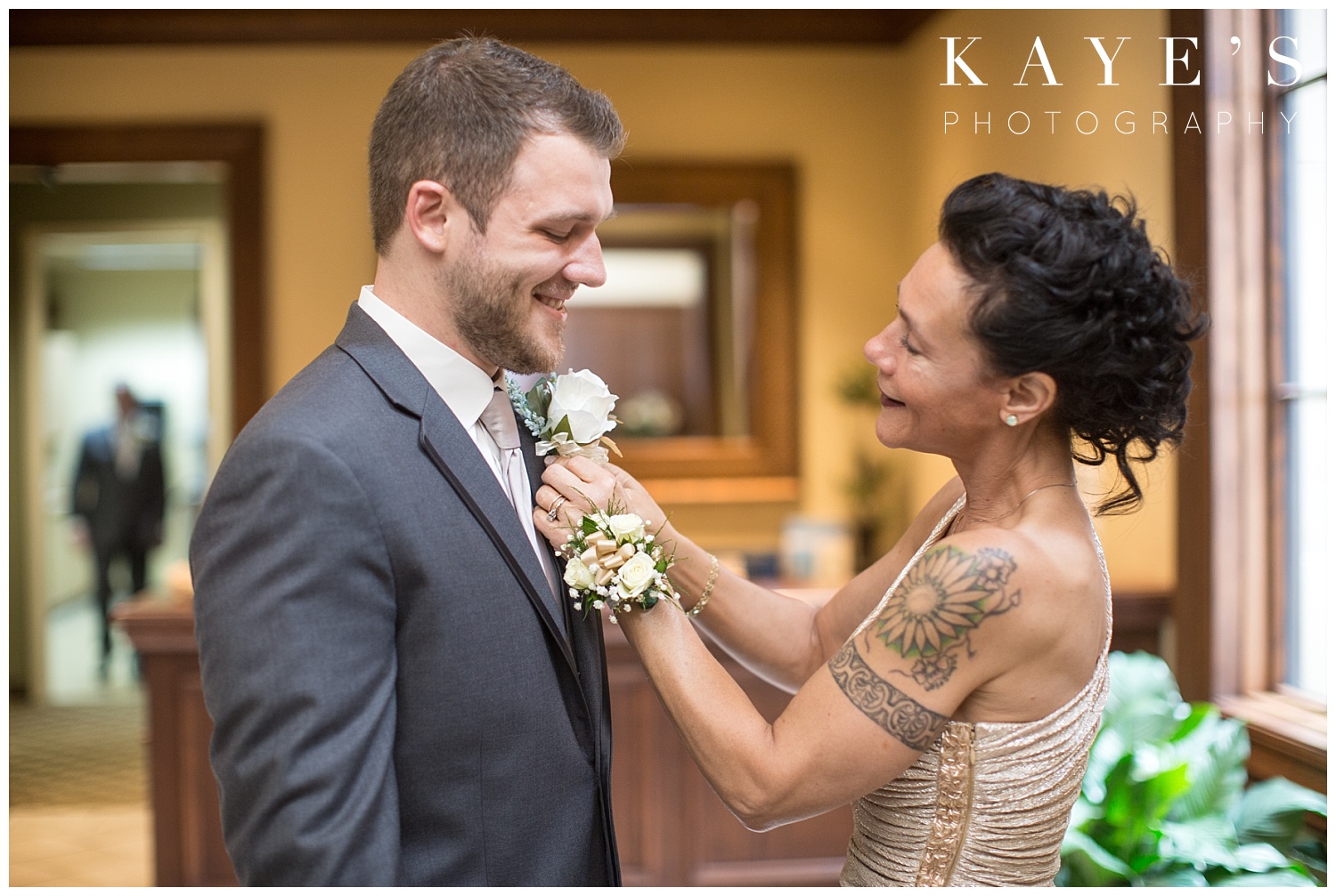 mother of groom putting flower on groom before wedding ceremony