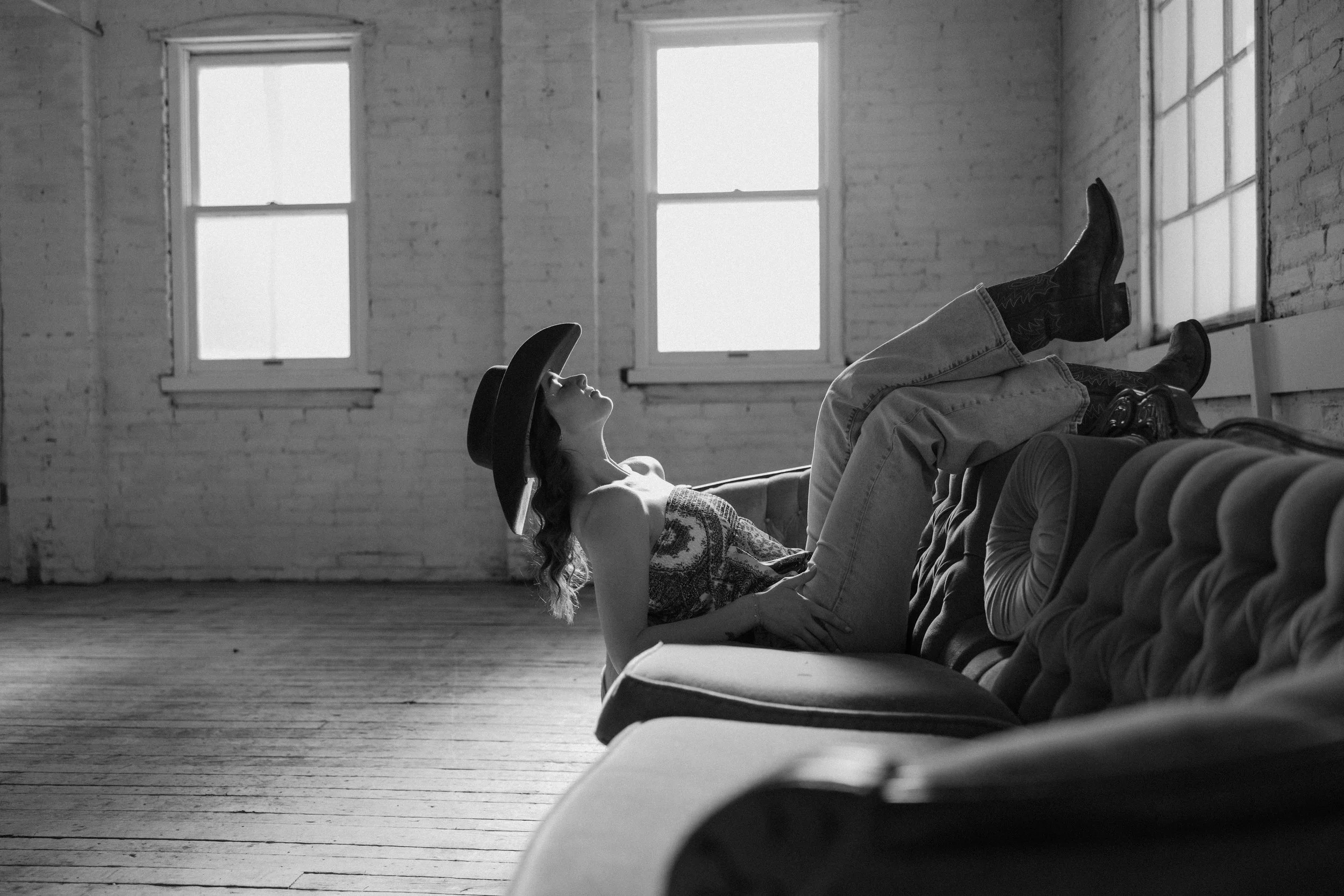 A man and woman lying on their sides in a grassy field, close and touching foreheads, sharing an intimate moment.