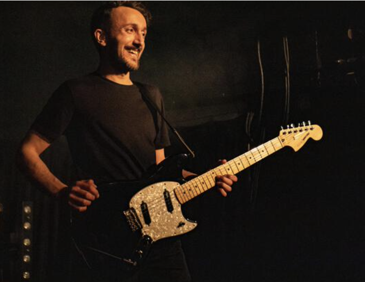 A photo of Robin Southby holding a Fender Mustang guitar