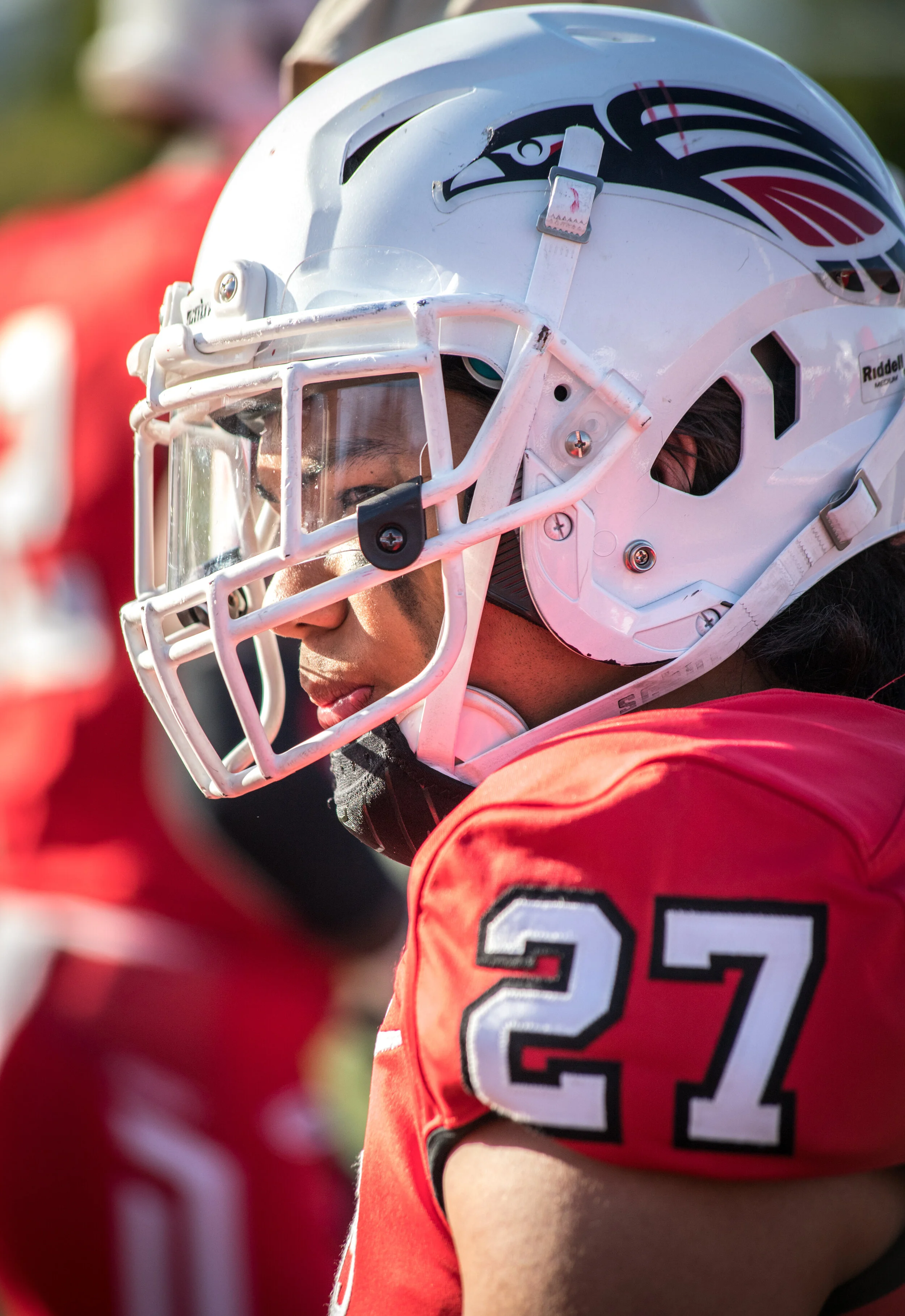 An American football player wearing a white helmet with a black and red logo and a red jersey with the number 27.