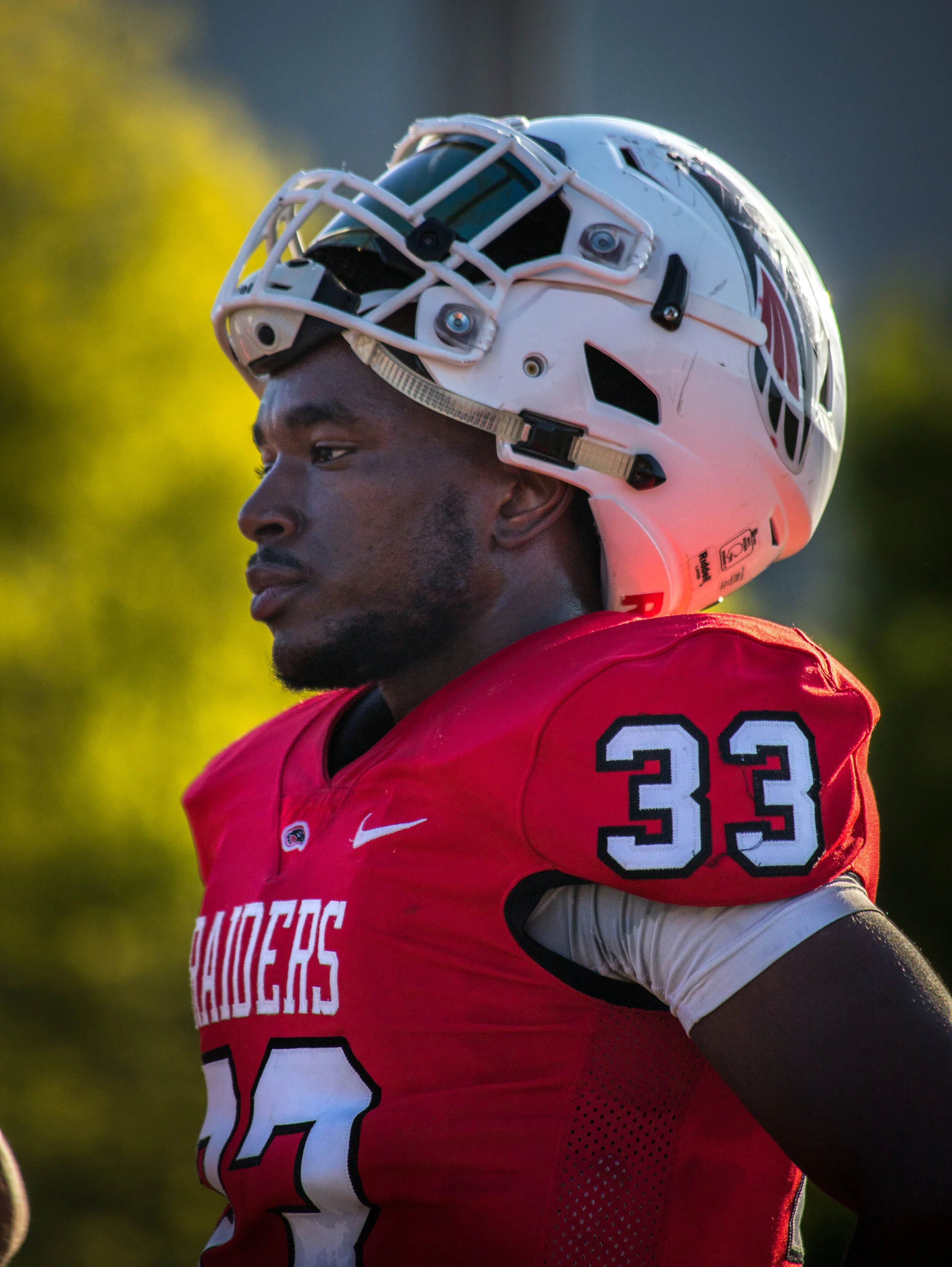 A football player wearing a red jersey with the number 33 and a white helmet with a faceguard.