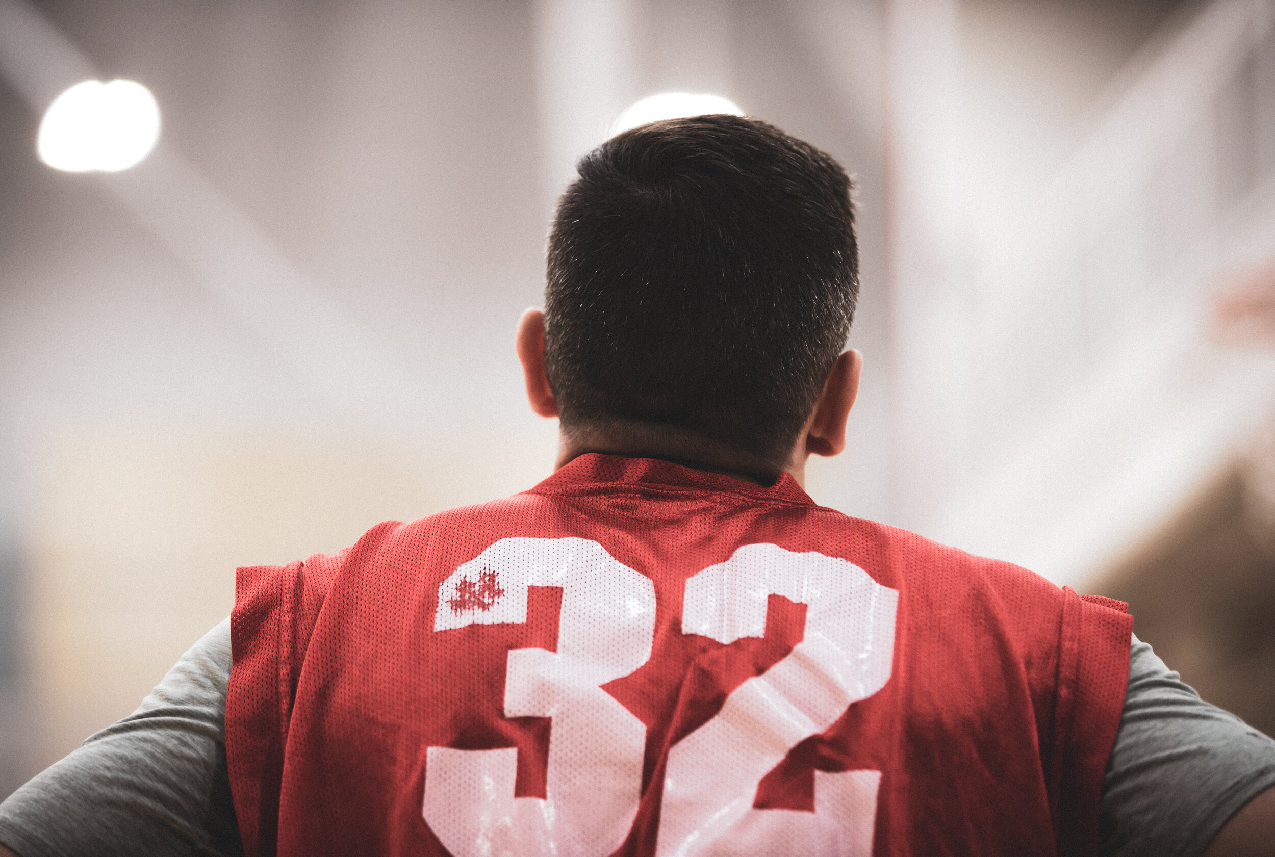 Back of a football player wearing a red jersey with the number 32, standing in an indoor facility.