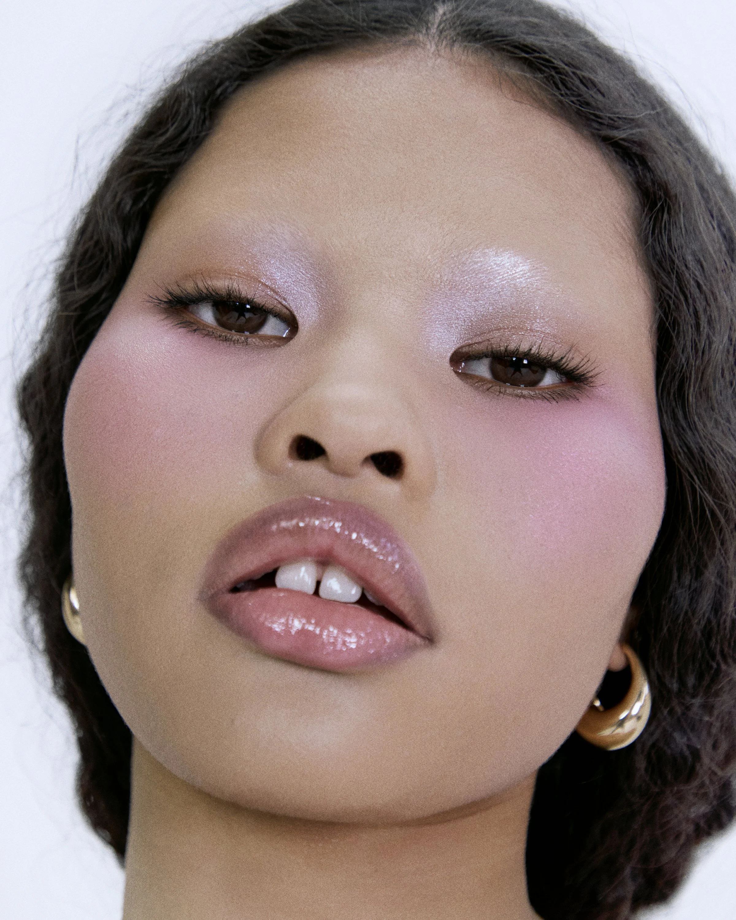 los angeles new york beauty photographer natural dewy skin. High fashion model with purple eyeshadow and pink blush gold earrings. Model is Bianca tooth gap