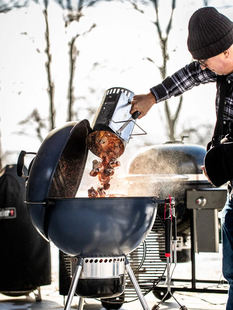 Mike Lang dumping charcoal into a Weber Kettle with one hand while he recovers from rotator cuff surgery