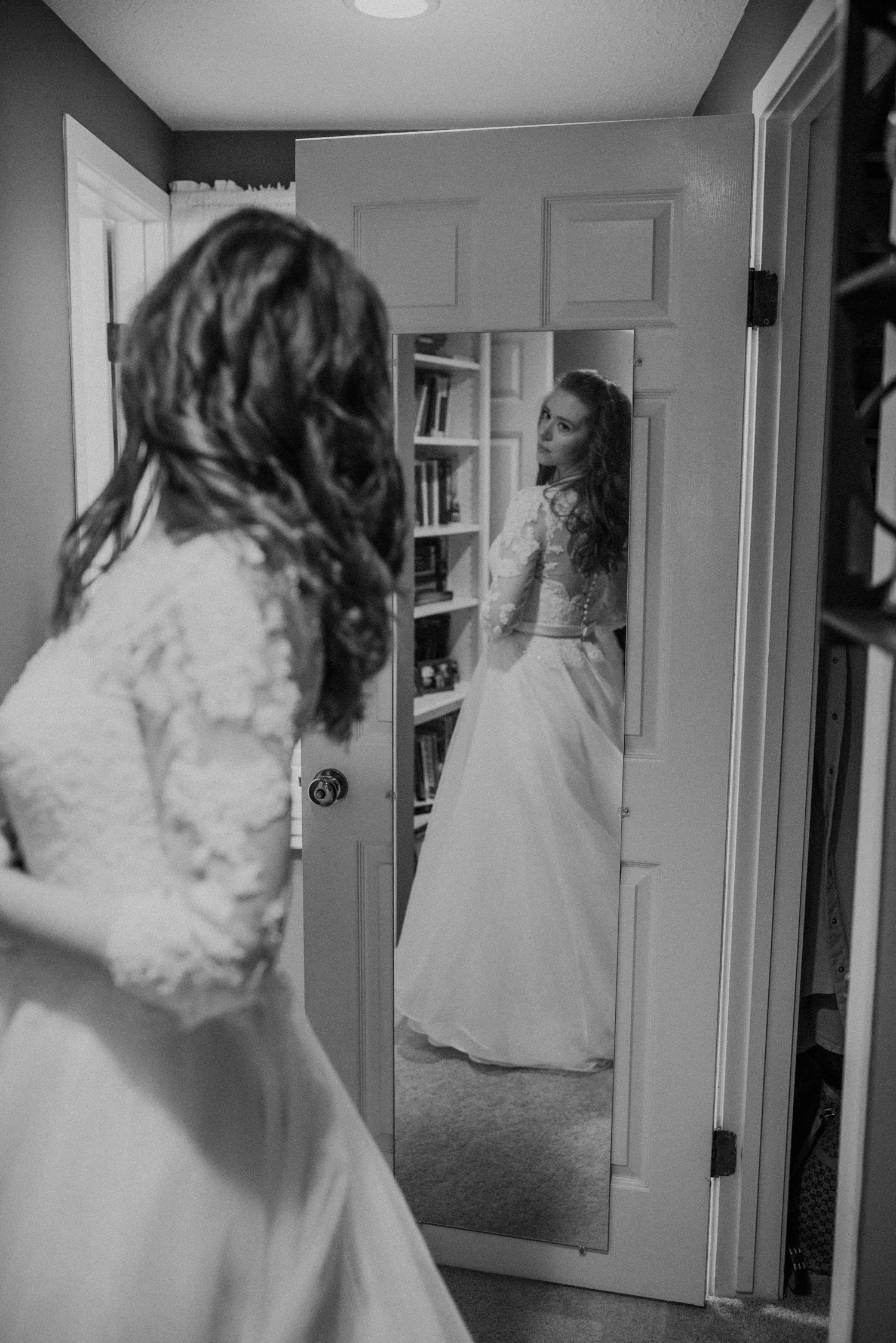 black and white bride getting ready and looking at dress in the mirror