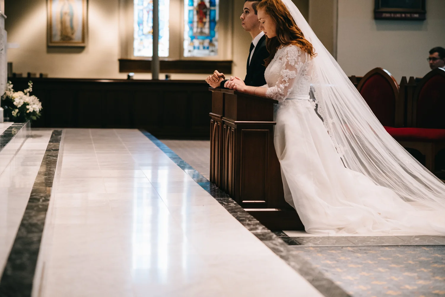bride and groom kneel before altar at old saint mary catholic church