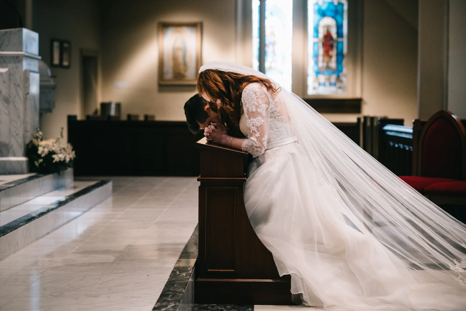 bride and groom pray during catholic wedding mass