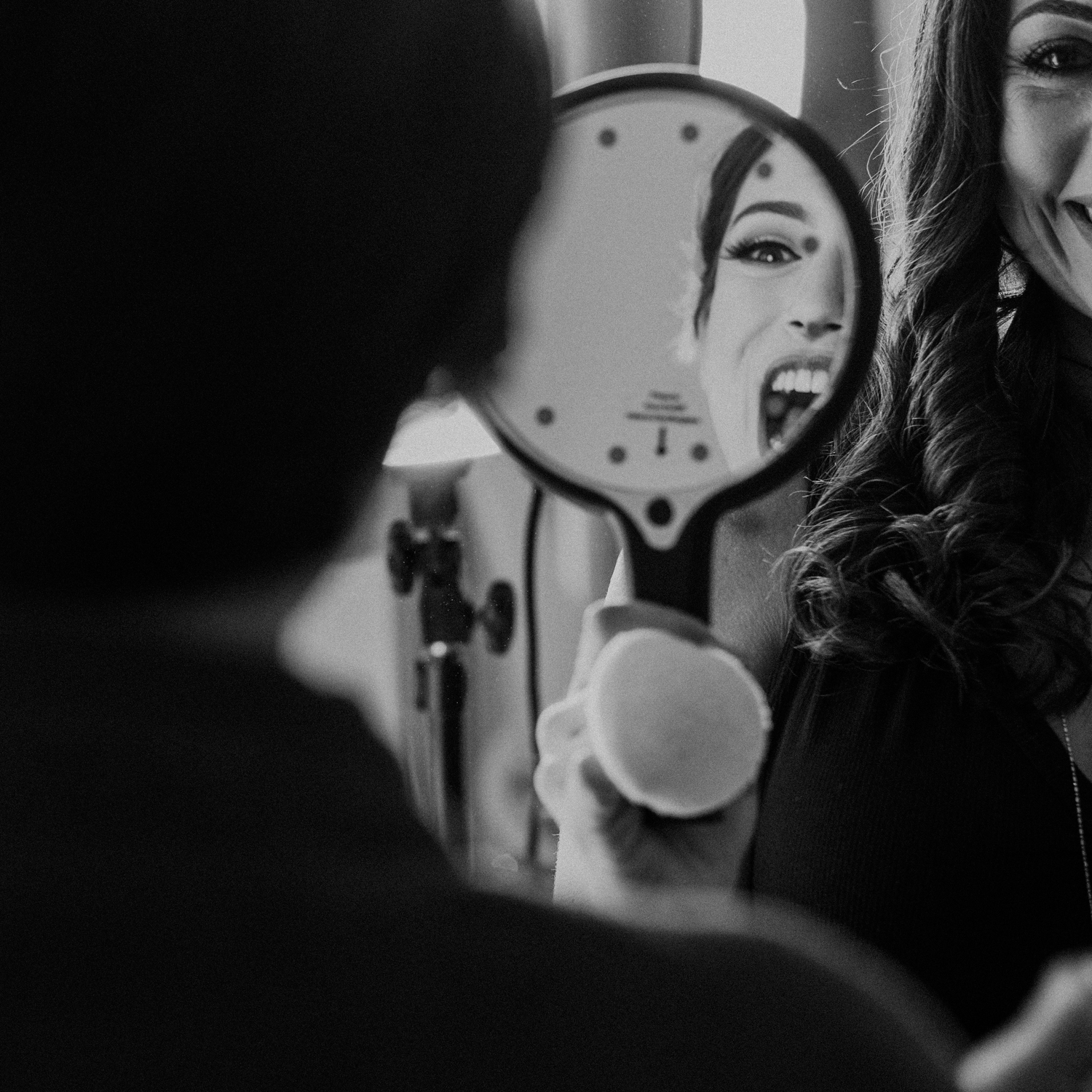 bride with huge smile in mirror as she sees her makeup before wedding