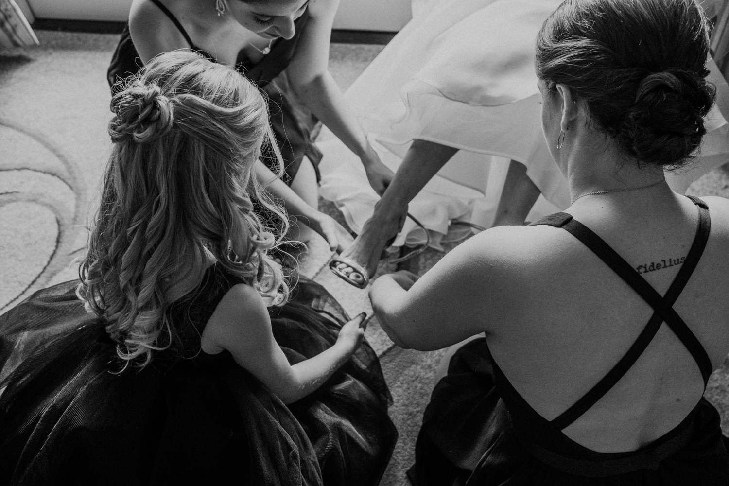 bridesmaids help put the bride's shoes on before virginia wedding