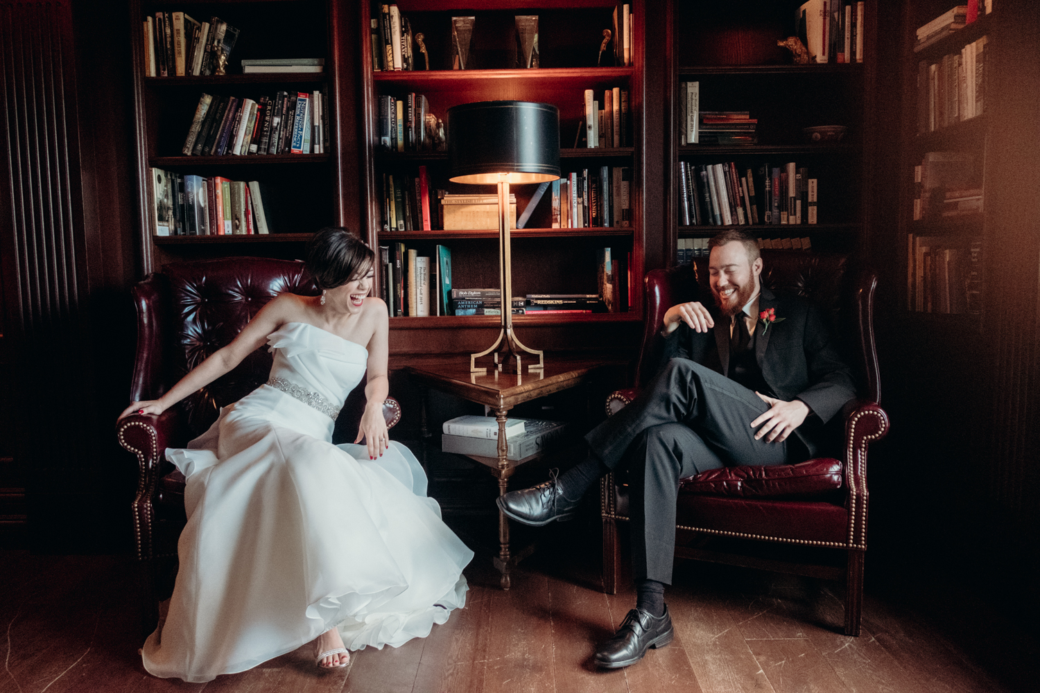 bride and groom sit and laugh before their wedding in the library at Salamander Resort and Spa