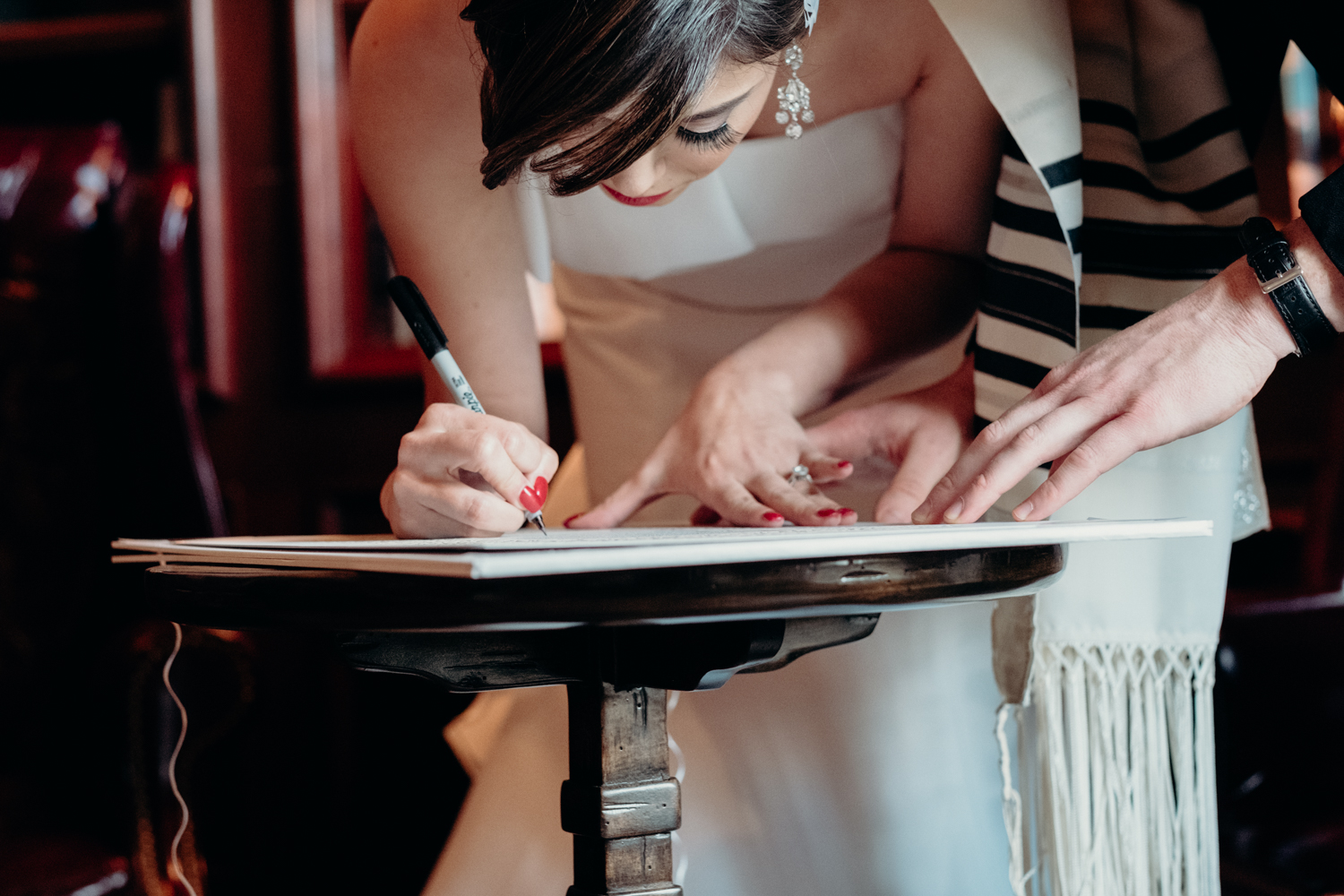 bride signs her name on the Ketubah