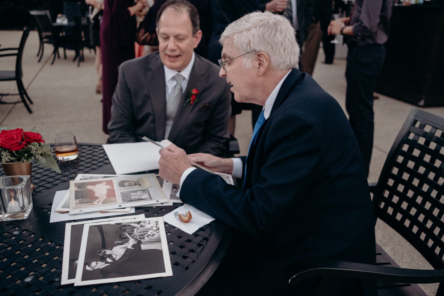 father of groom and guests look at old wedding photos during cocktail hour