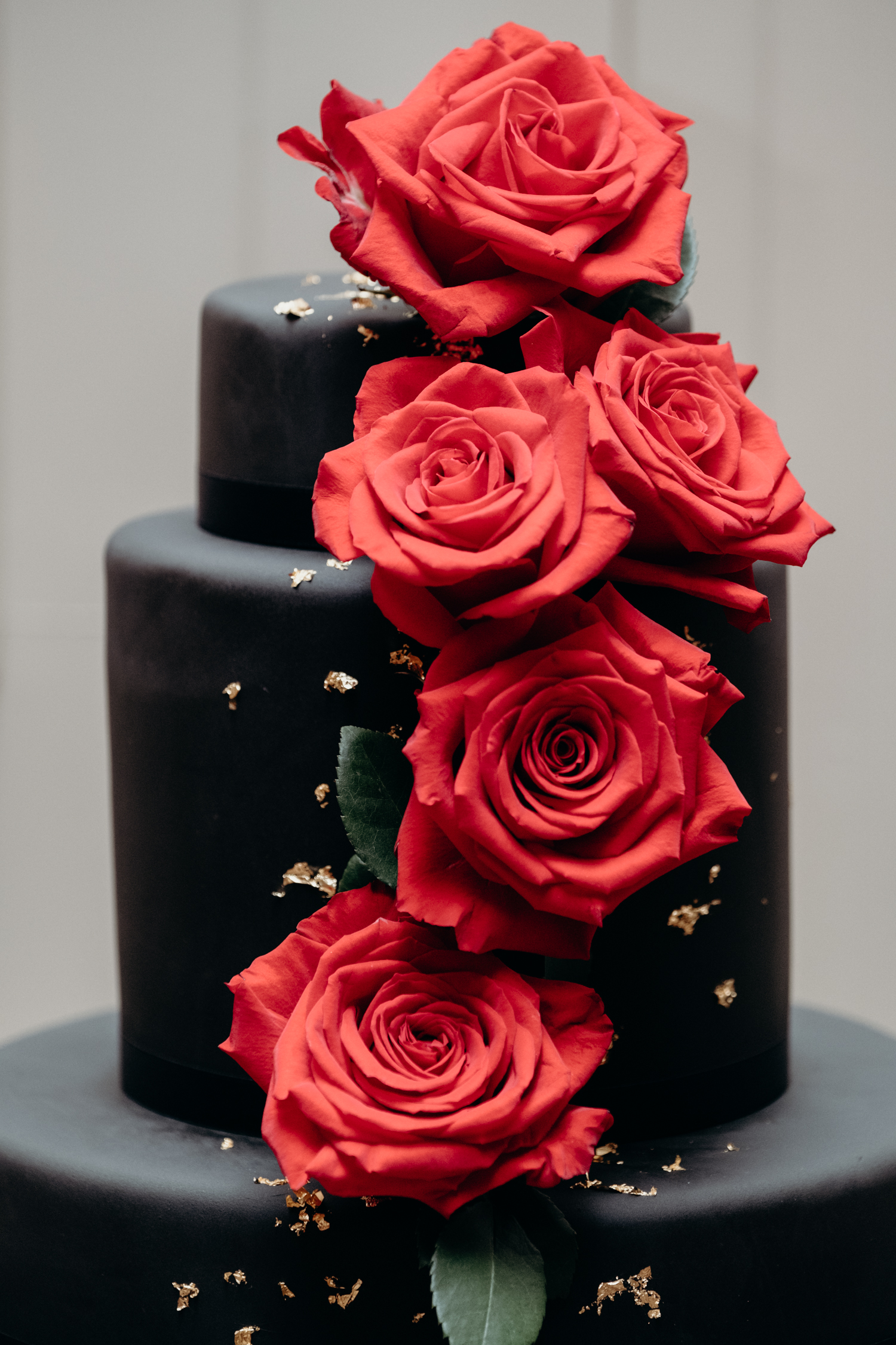 black and gold cake with red roses up close at middleburg wedding