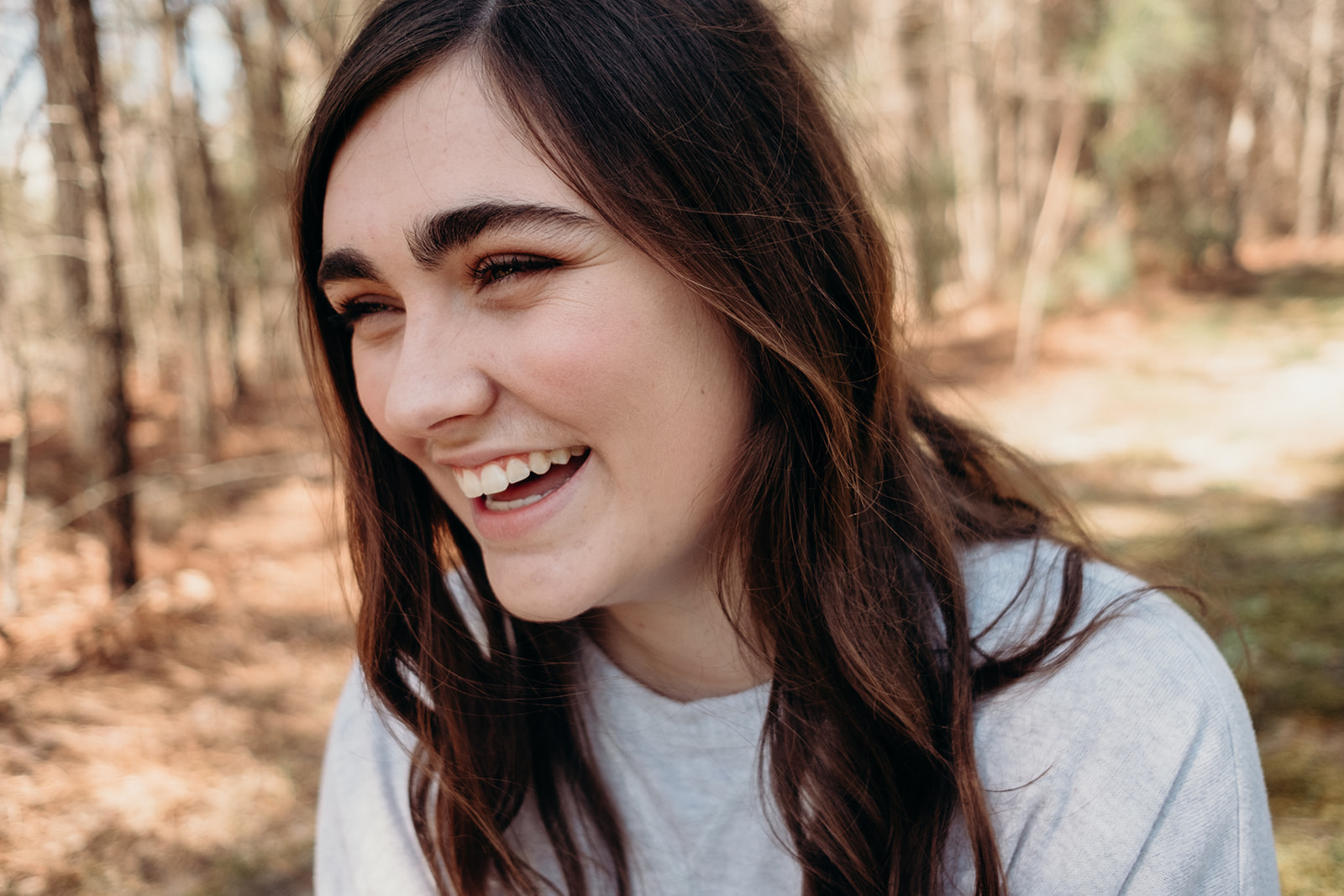 A girl laughs while enjoy the spring during her senior portrait photo session. 
