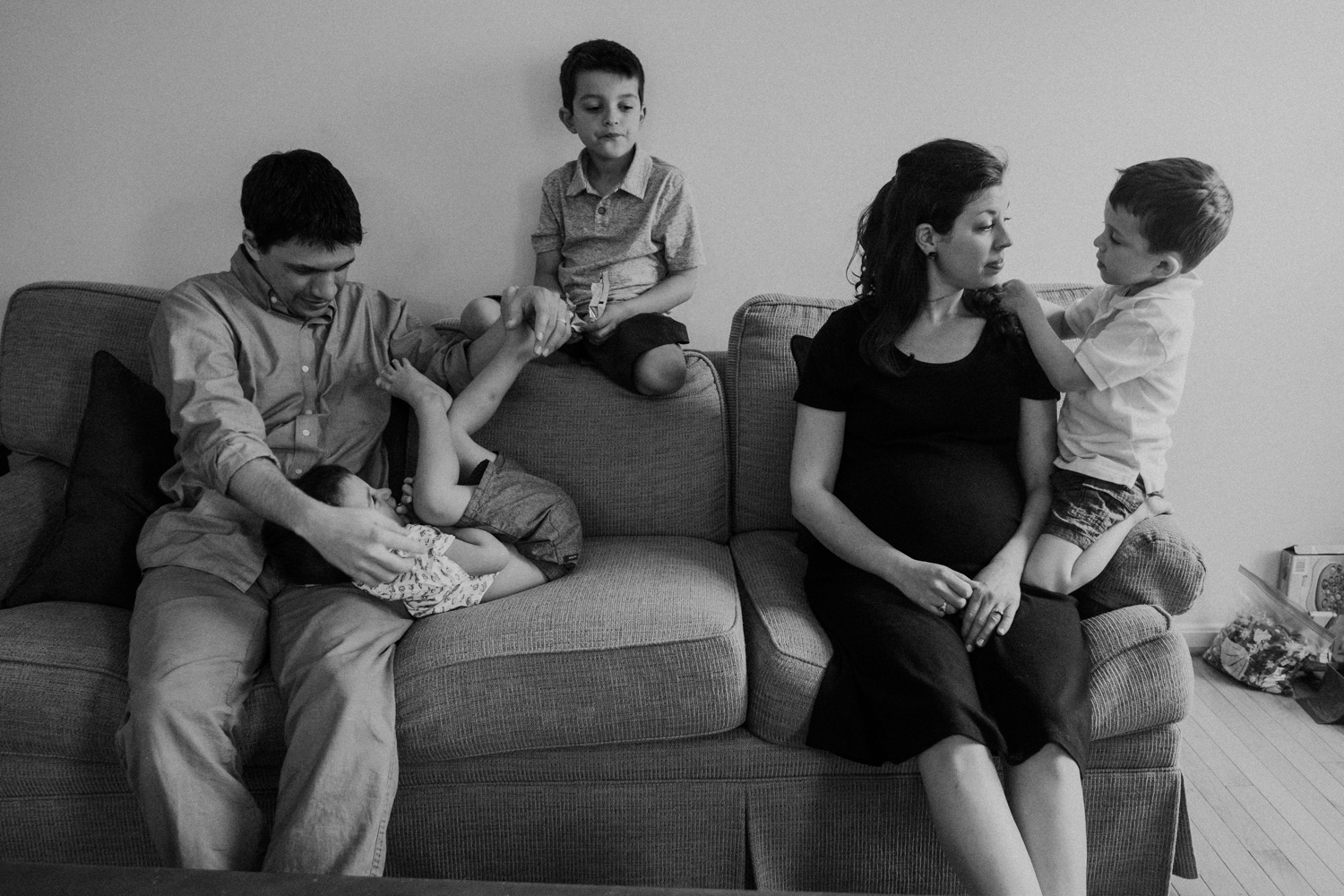 A mother and father are surrounded by their 3 boys while expecting their fourth child. 