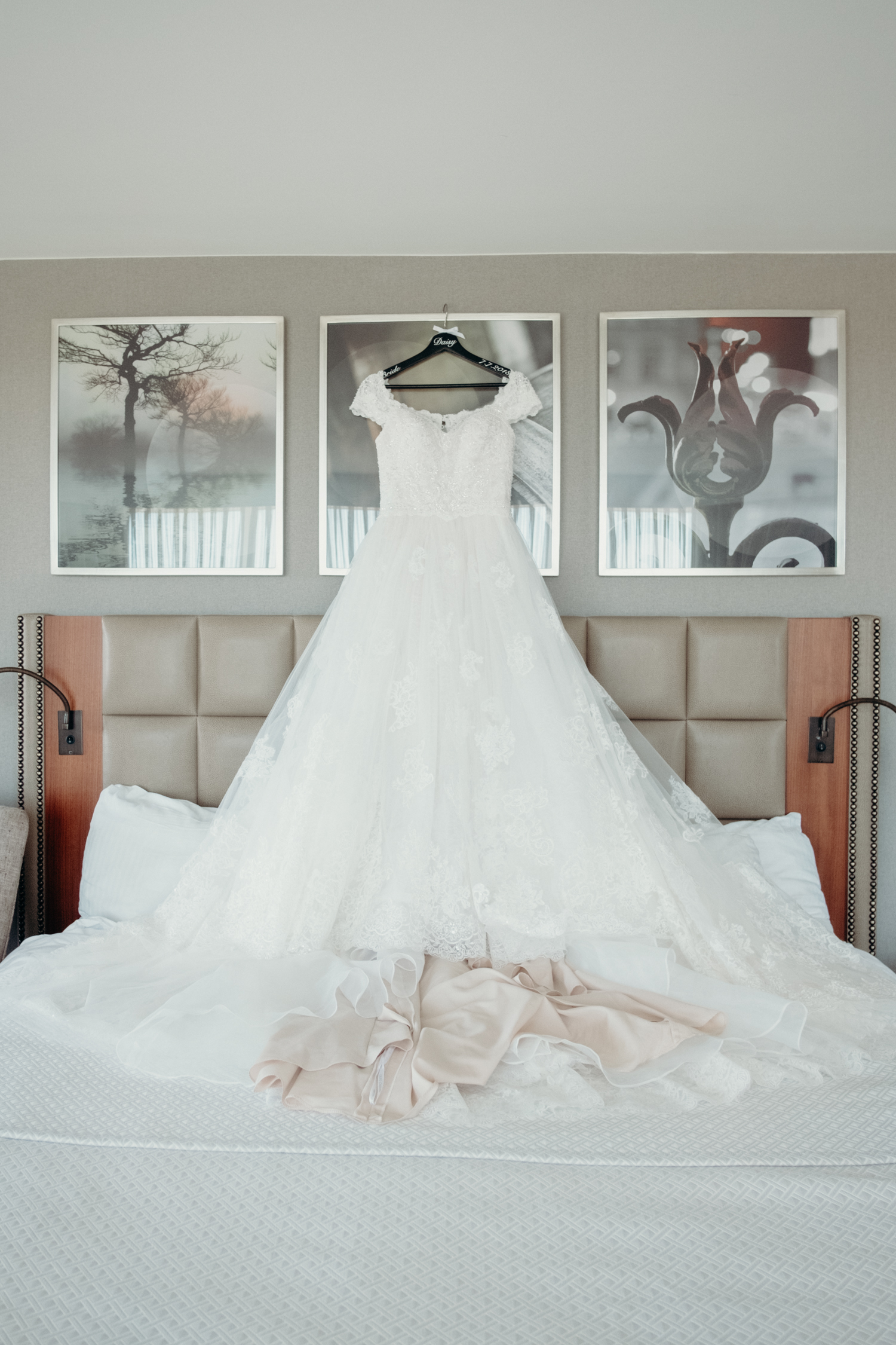 A bride's a-line wedding dress hangs above a bed at Lansdowne Resort.