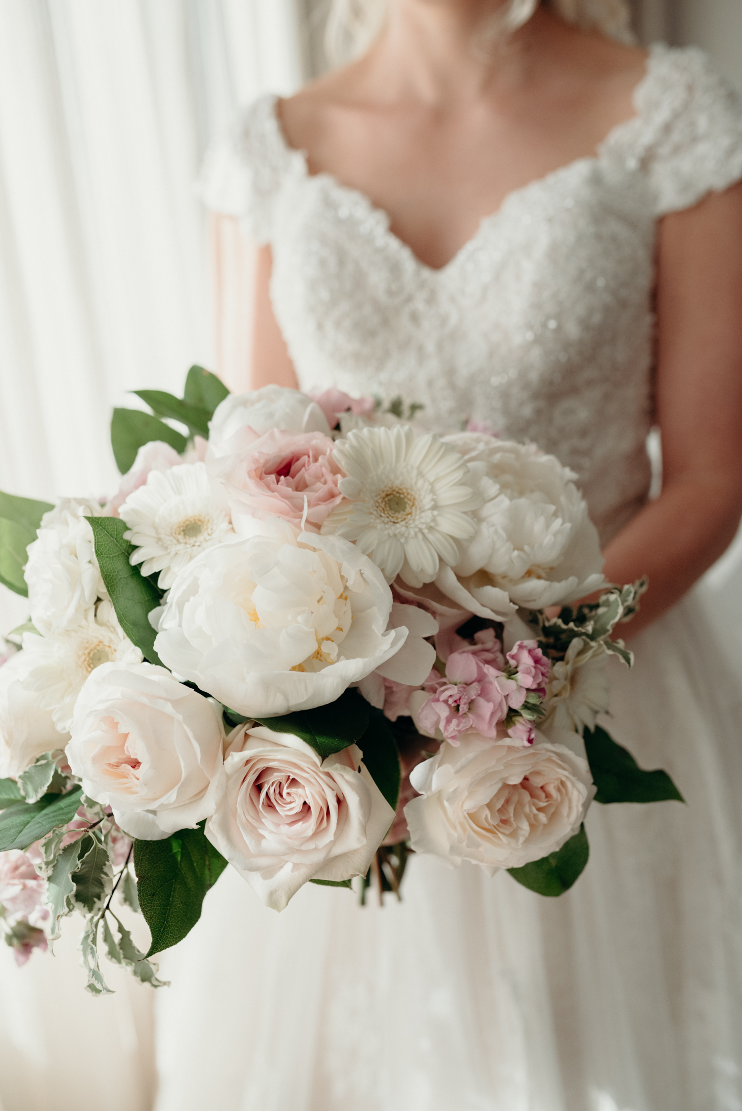 A bride holds a bouquet of of pink and white flowers on her wedding day at Lansdowne Resort.
