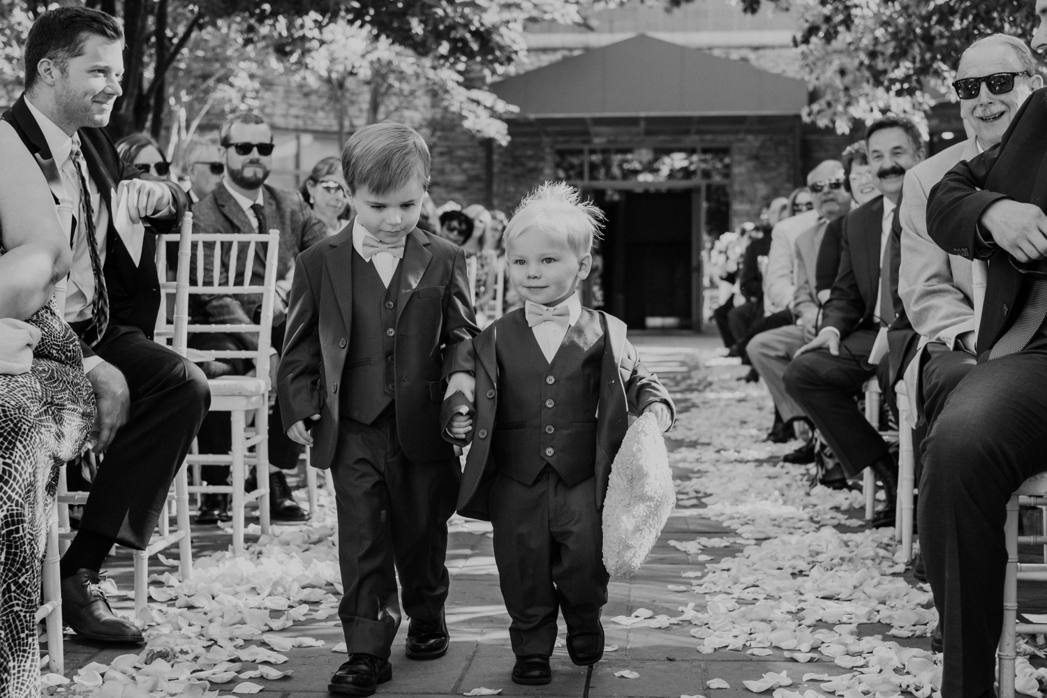 A pair of ring bearers in suits and bowties walk up the aisle at a wedding ceremony at Lansdowne Resort. 
