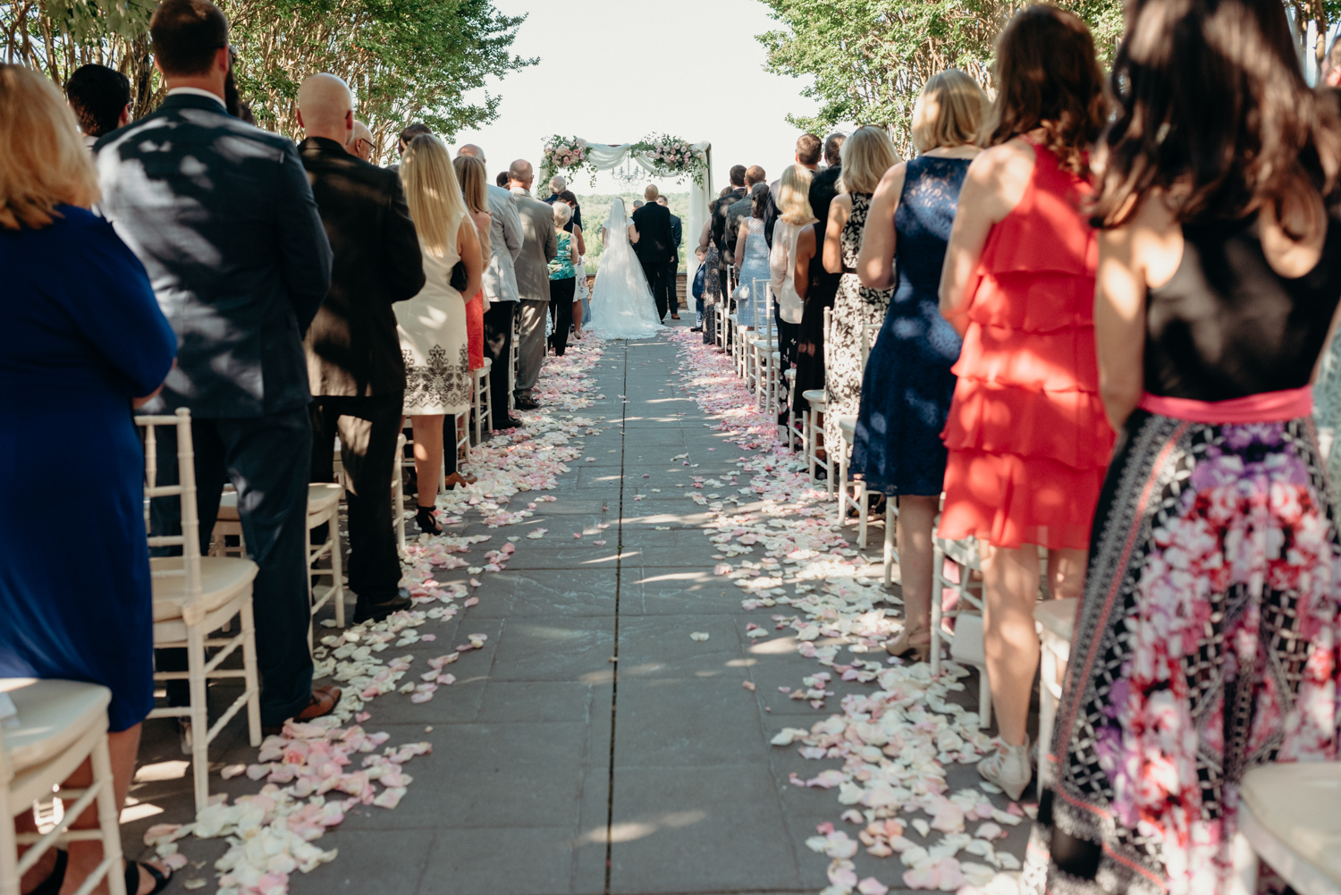 A crowd of guests looks down an aisle lined with rose petals during a wedding ceremony at Lansdowne resort.