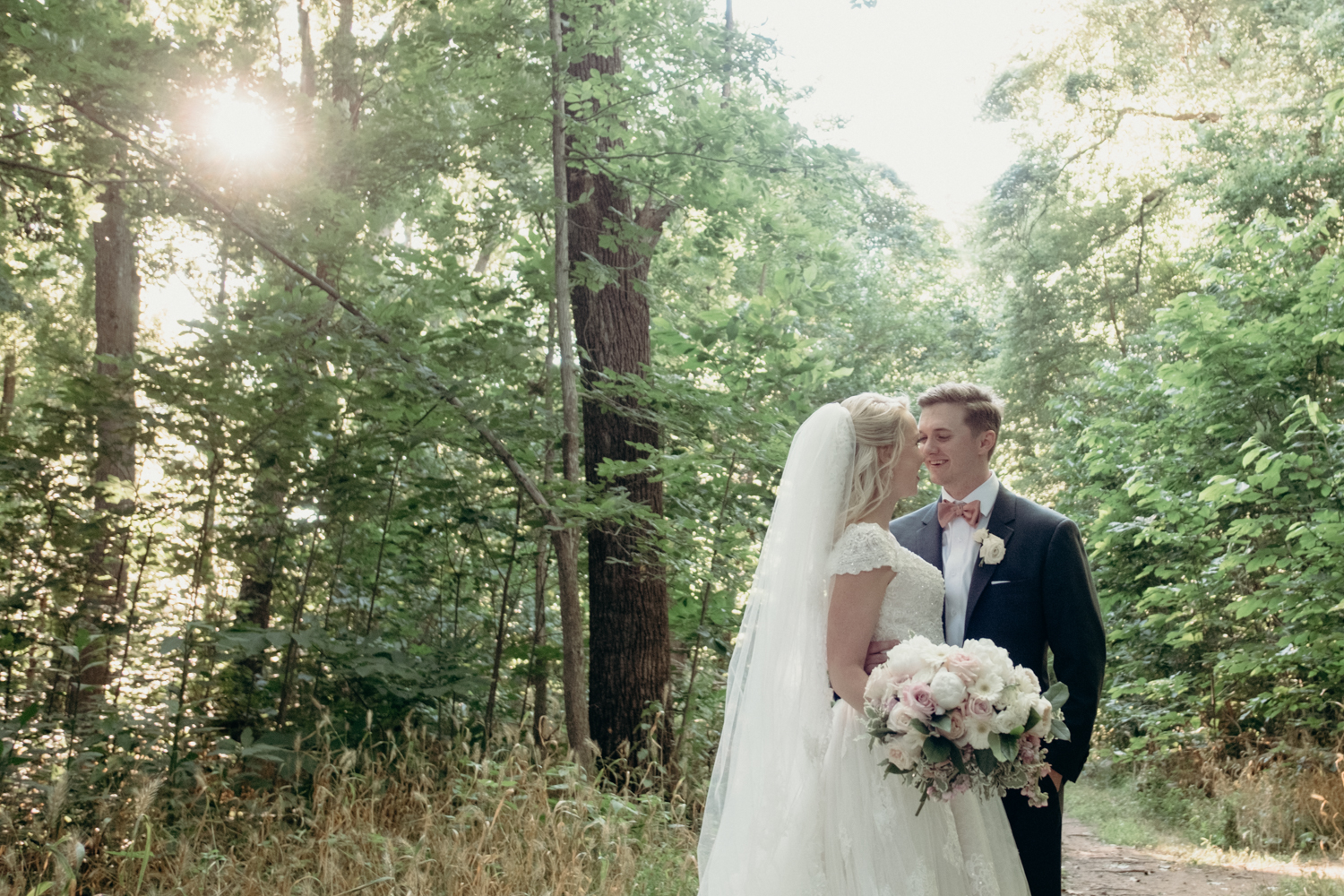 A husband and wife smile at one another in the woods after their outdoor wedding ceremony at Lansdowne Resort.