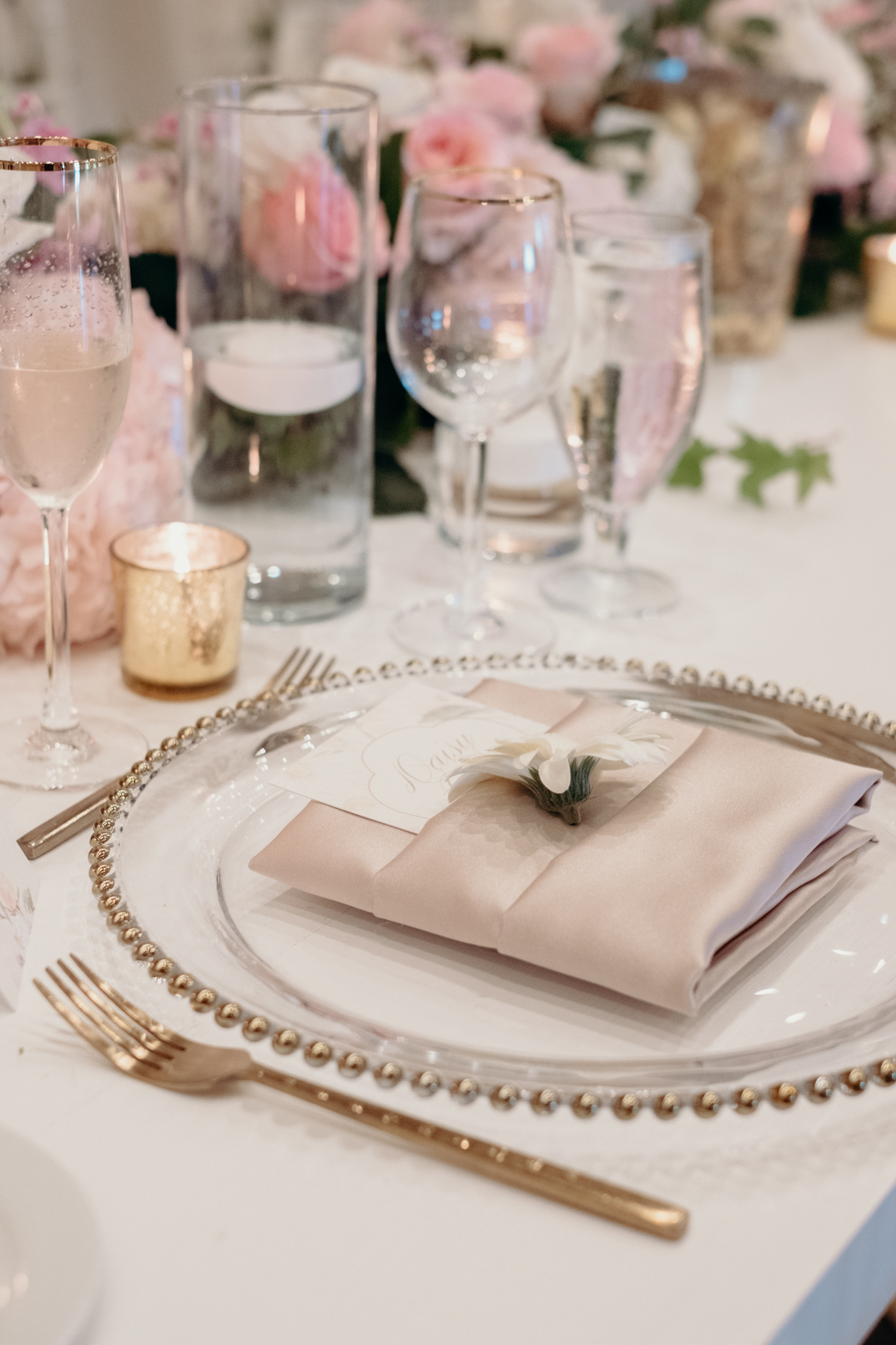 A cream and blush table setting is accented with a white daisy and menu at a wedding reception at Lansdowne Resort. 