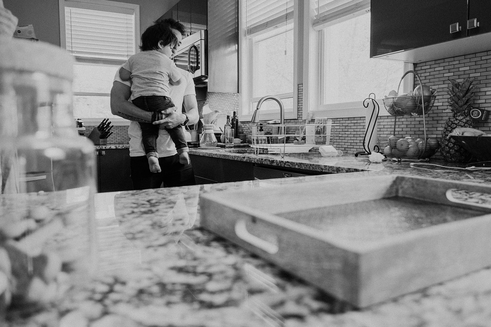 A father holds his son in the kitchen of their DC home during an in-home family photography session. 