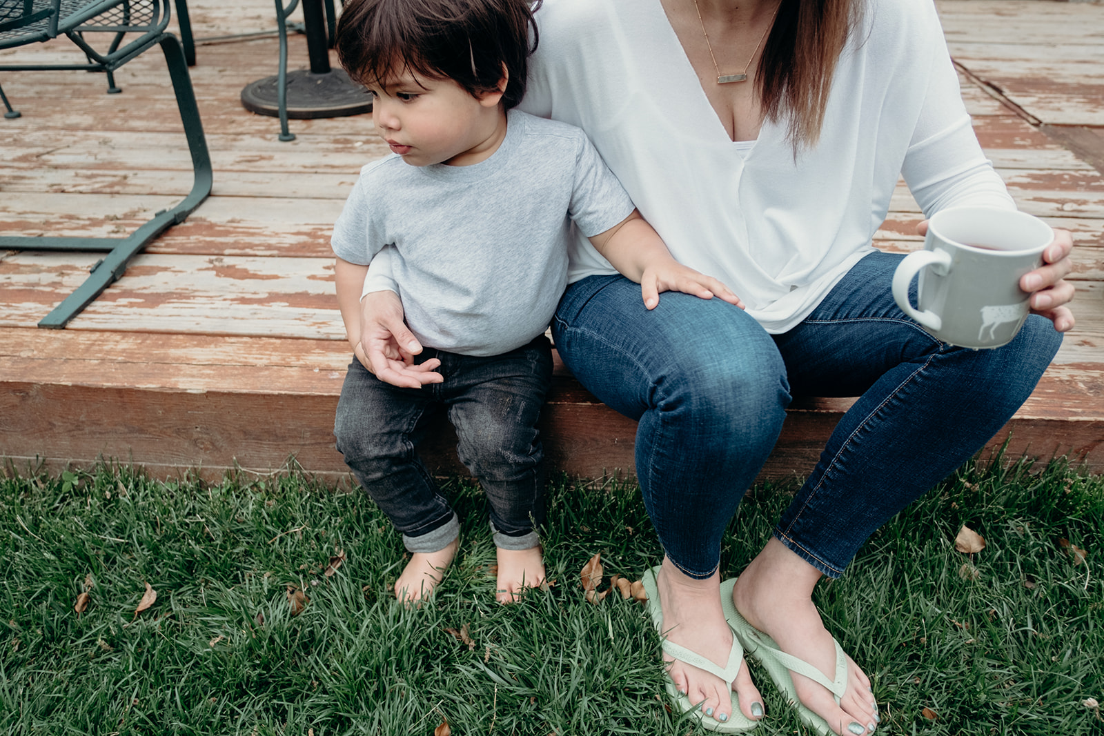 A son sits next to his mother while she sips coffee on the back deck of their DC home during an in-home family photography session. 