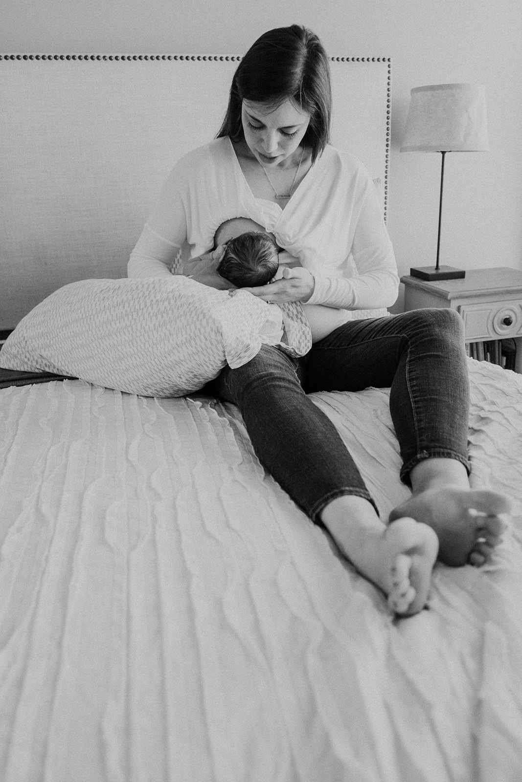 A mother nurses her newborn son on her bed during an in-home family photography session. 