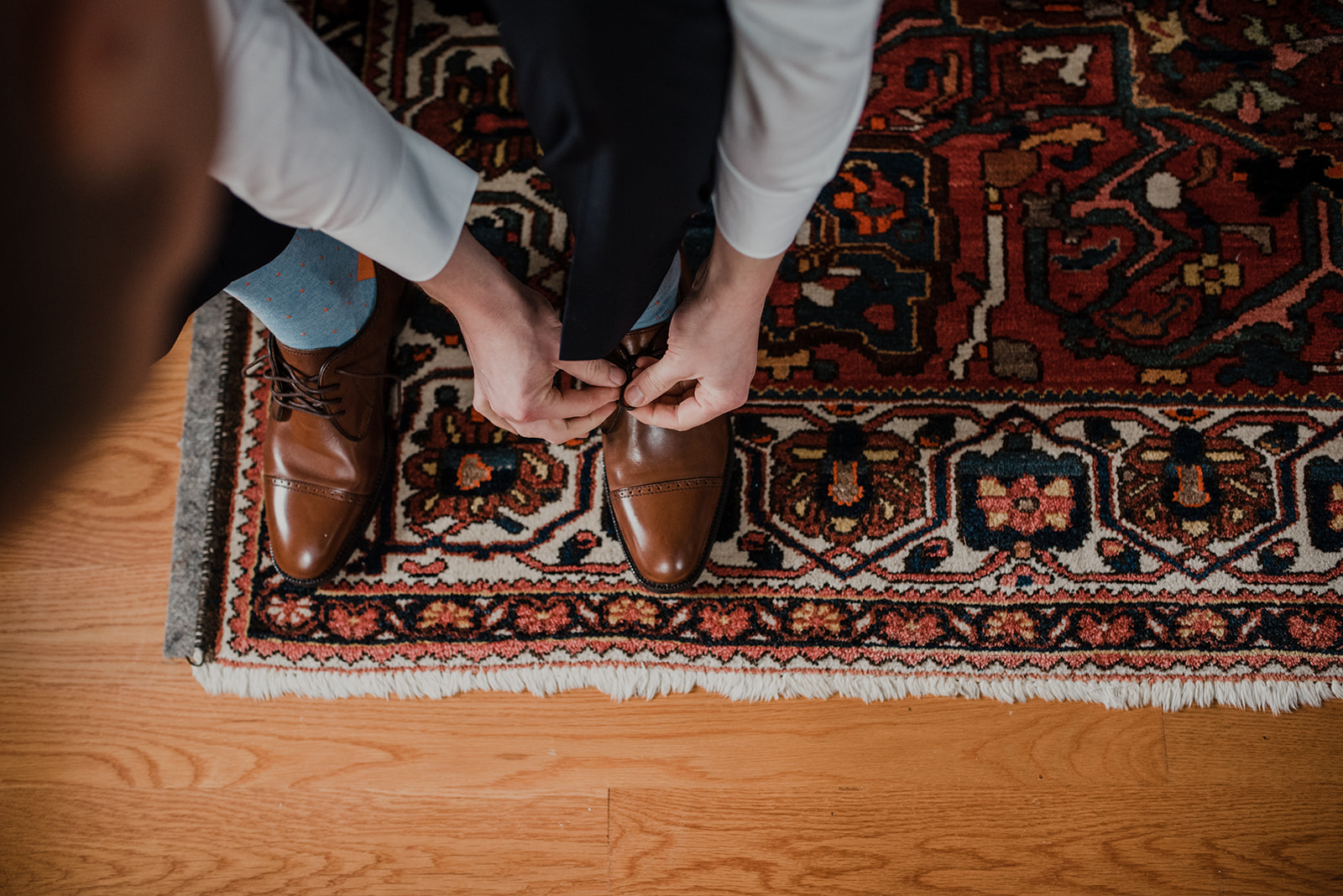 The groom ties his shoes before his outdoor spring wedding ceremony at Blue Hill Farm in Waterford, VA. 