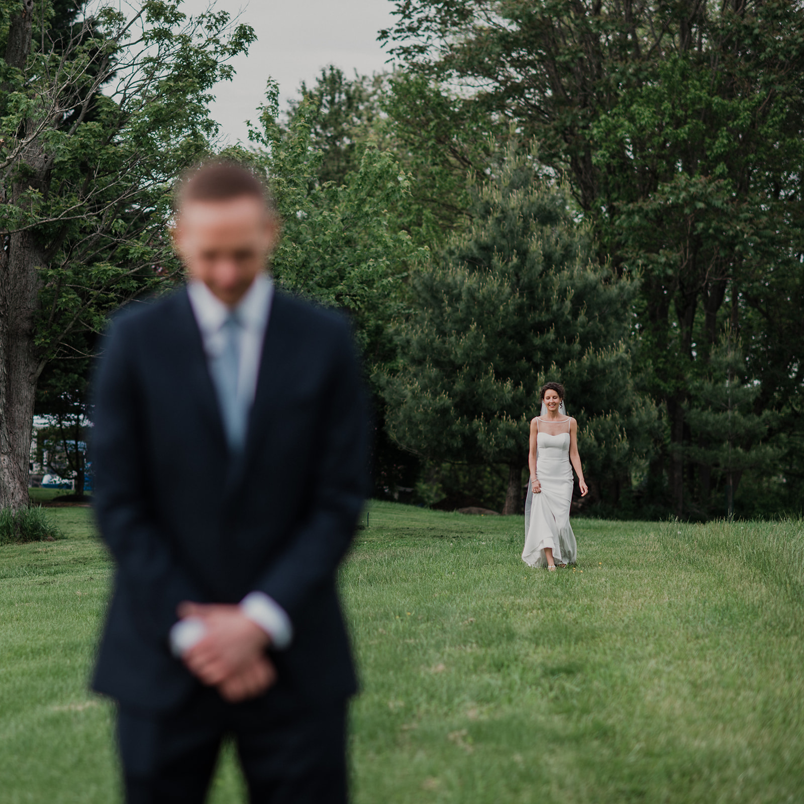 A groom waits while his bride walks up behind him for a first look before their outdoor wedding ceremony at Blue Hill Farm in Waterford, VA. 