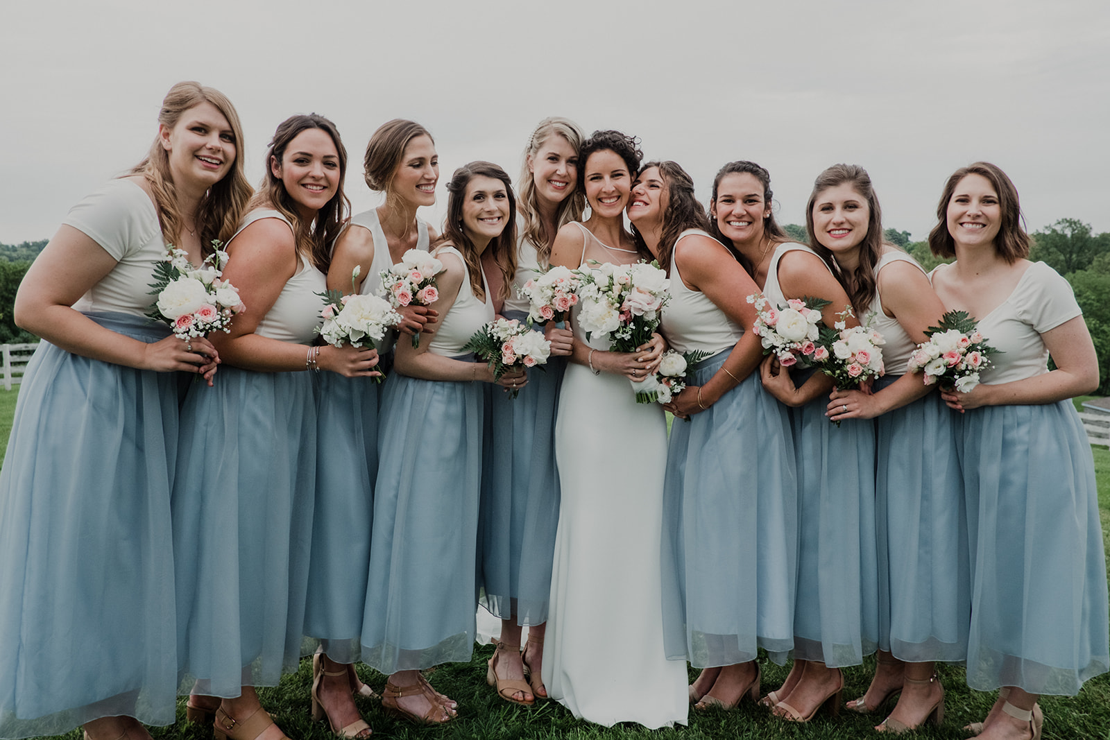 Bridesmaids gather around the bride after her outdoor wedding ceremony at Blue Hill Farm in Waterford, VA.