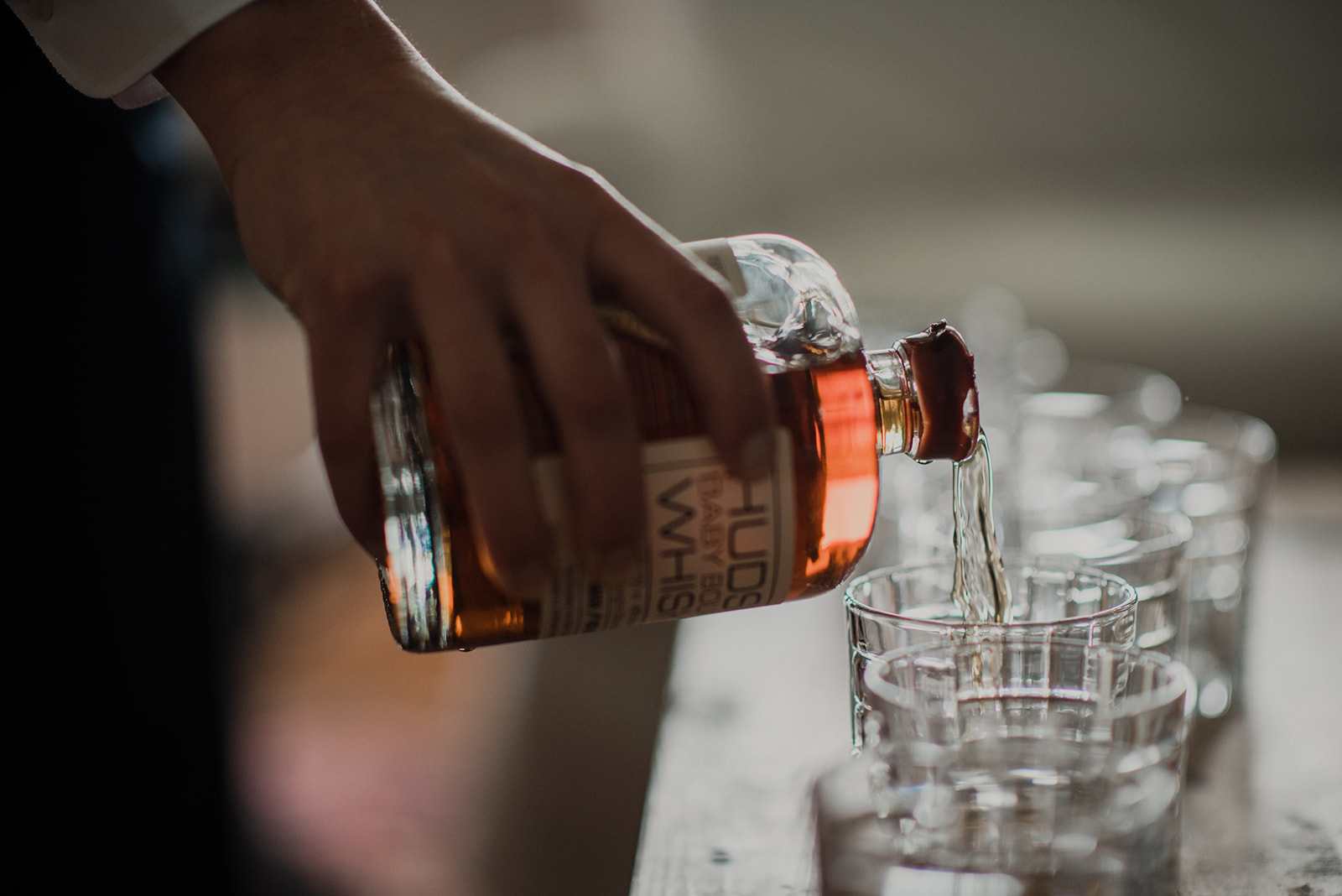 A groomsman pours bourbon into glasses for a toast before an outdoor wedding ceremony at Blue Hill Farm in Waterford, VA. 