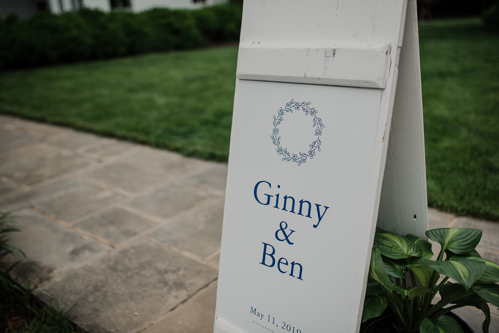The bride and groom's names appear on a sign outside of their outdoor wedding ceremony at Blue Hill Farm in Waterford, VA.