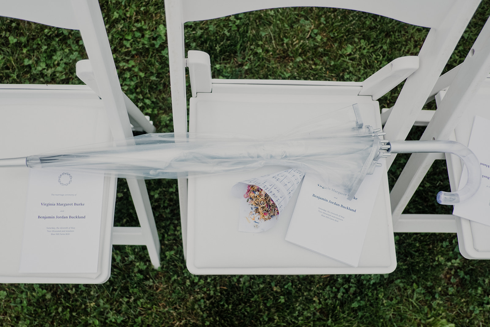 An umbrella sits next to the programs at an outdoor wedding ceremony at Blue Hill Farm in Waterford, VA.