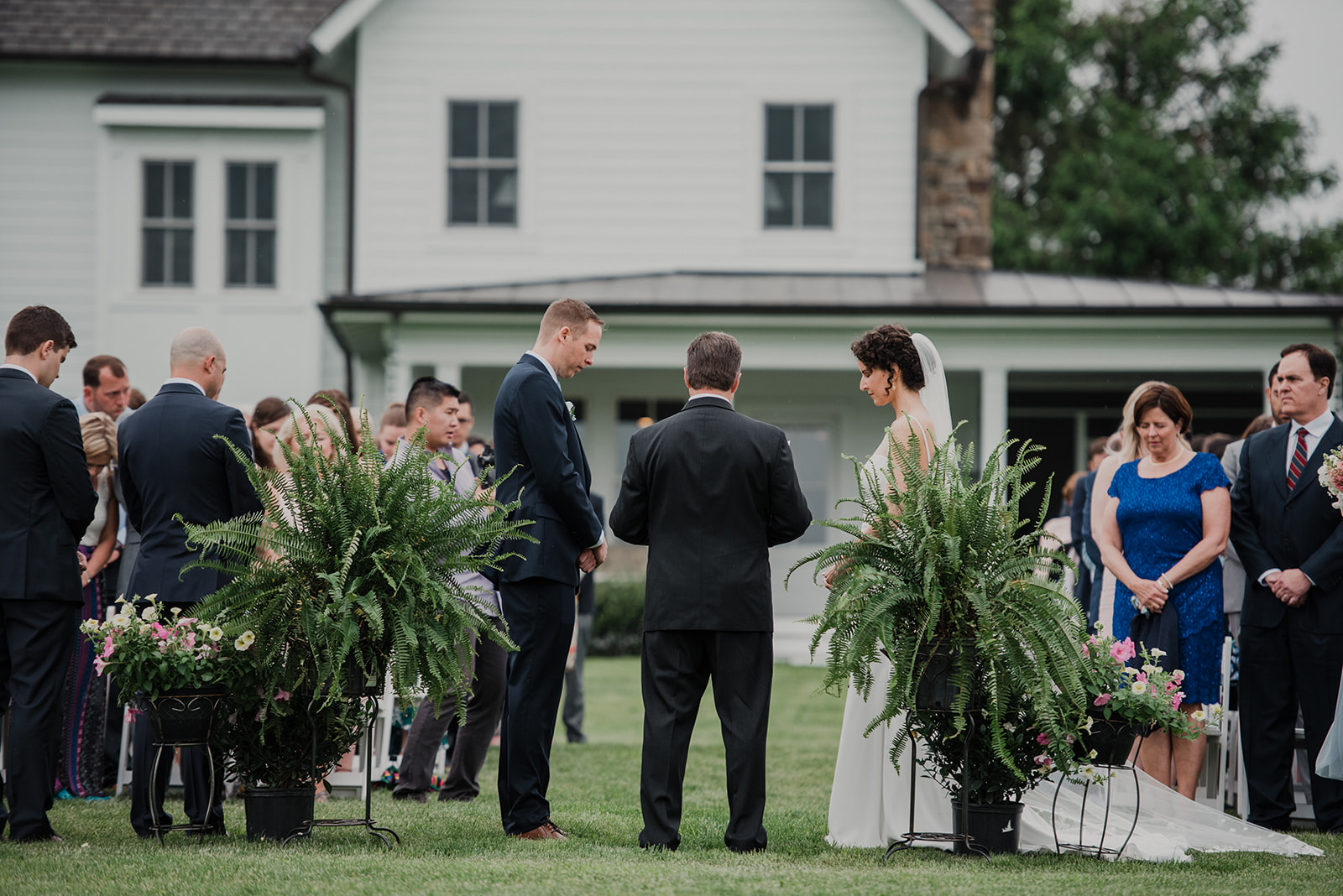 A bride and a groom get married between two ferns during their outdoor wedding ceremony at Blue Hill Farm in Waterford, VA.