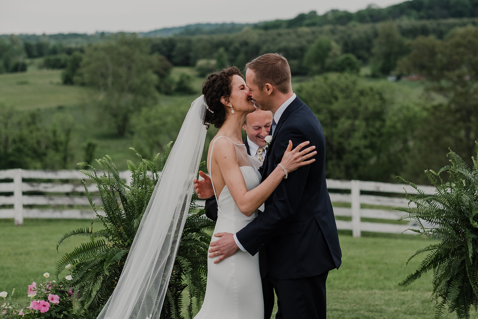 A bride and groom kiss after they are pronounced husband and wife during their outdoor wedding ceremony at Blue Hill Farm in Waterford, VA.