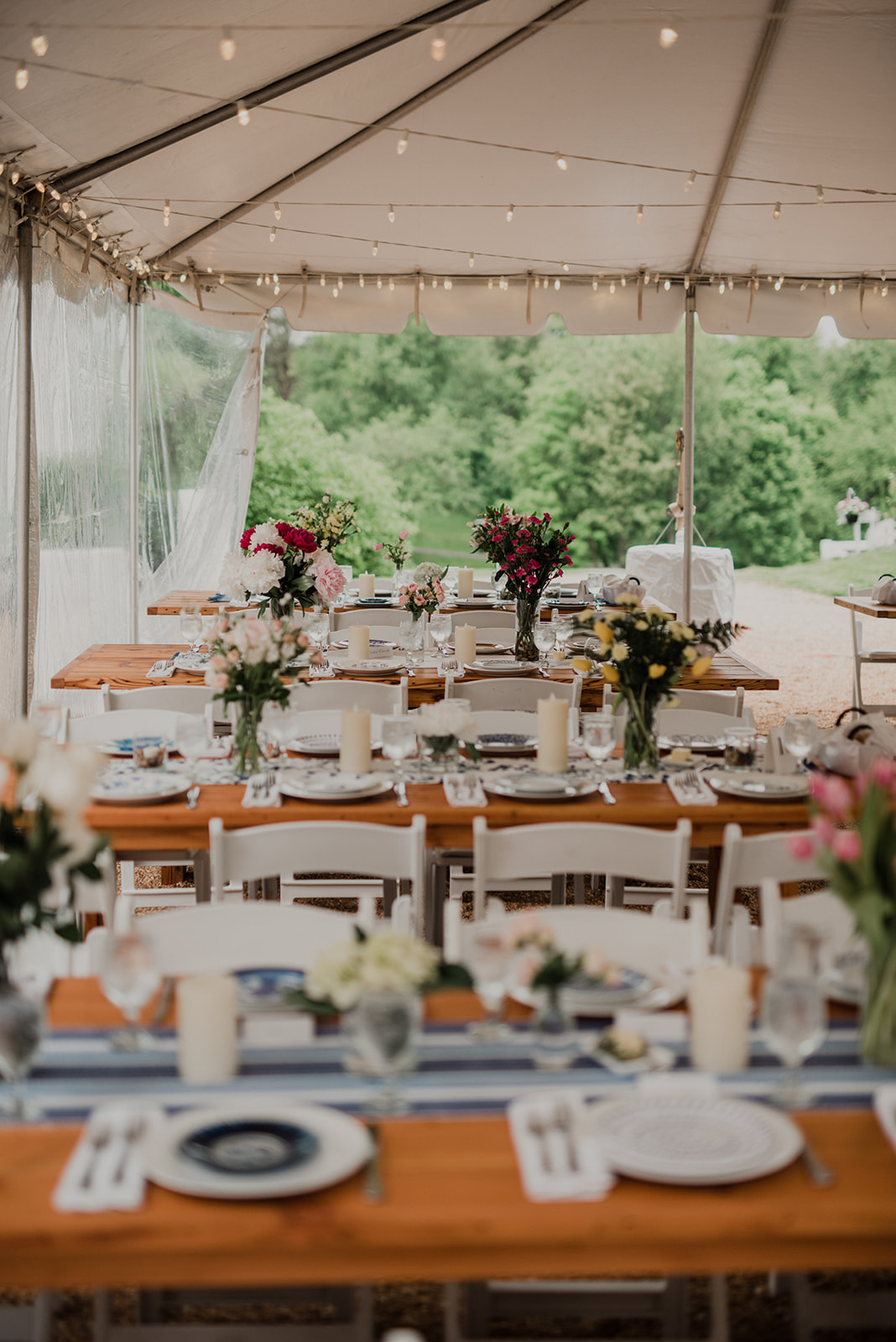 Farm tables are adorned with wildflower bouquets and blue ceramic plates at a wedding reception at Blue Hill Farm in Waterford, VA.
